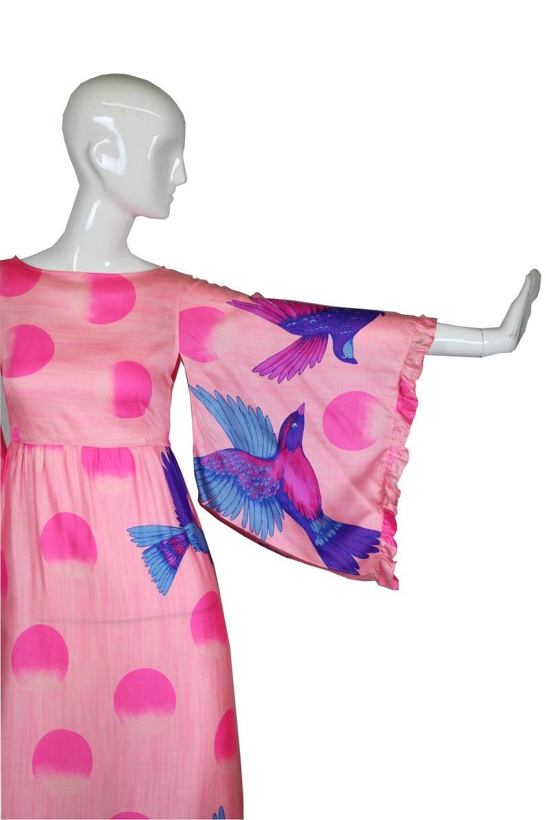 Hanae Mori rare 1970's screen printed pink kimono dress featuring a patterns of 3/4 moons and exotic birds in purple, blue and fuchsia. The dress has kimono angel wing sleeves, an empire waistline and fastens with the back with a zipper and