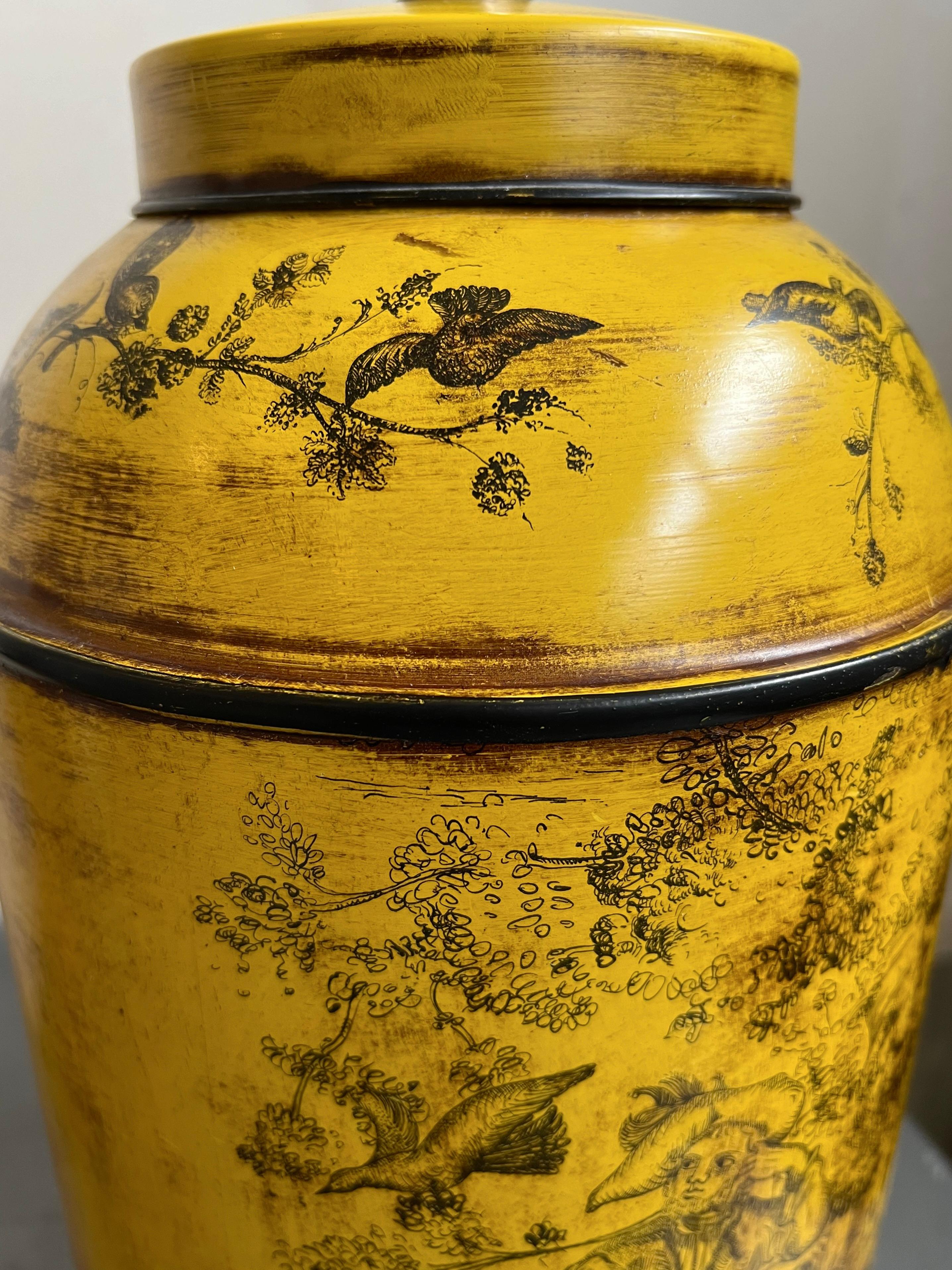 This is a 1970s French provincial-style Frederick Cooper French Tea Canister Lamp in vibrant light mustard-yellow. Delicate hand-painted French Country scenes are depicted throughout. The lamp sits on a round, conforming wood base. The neck is