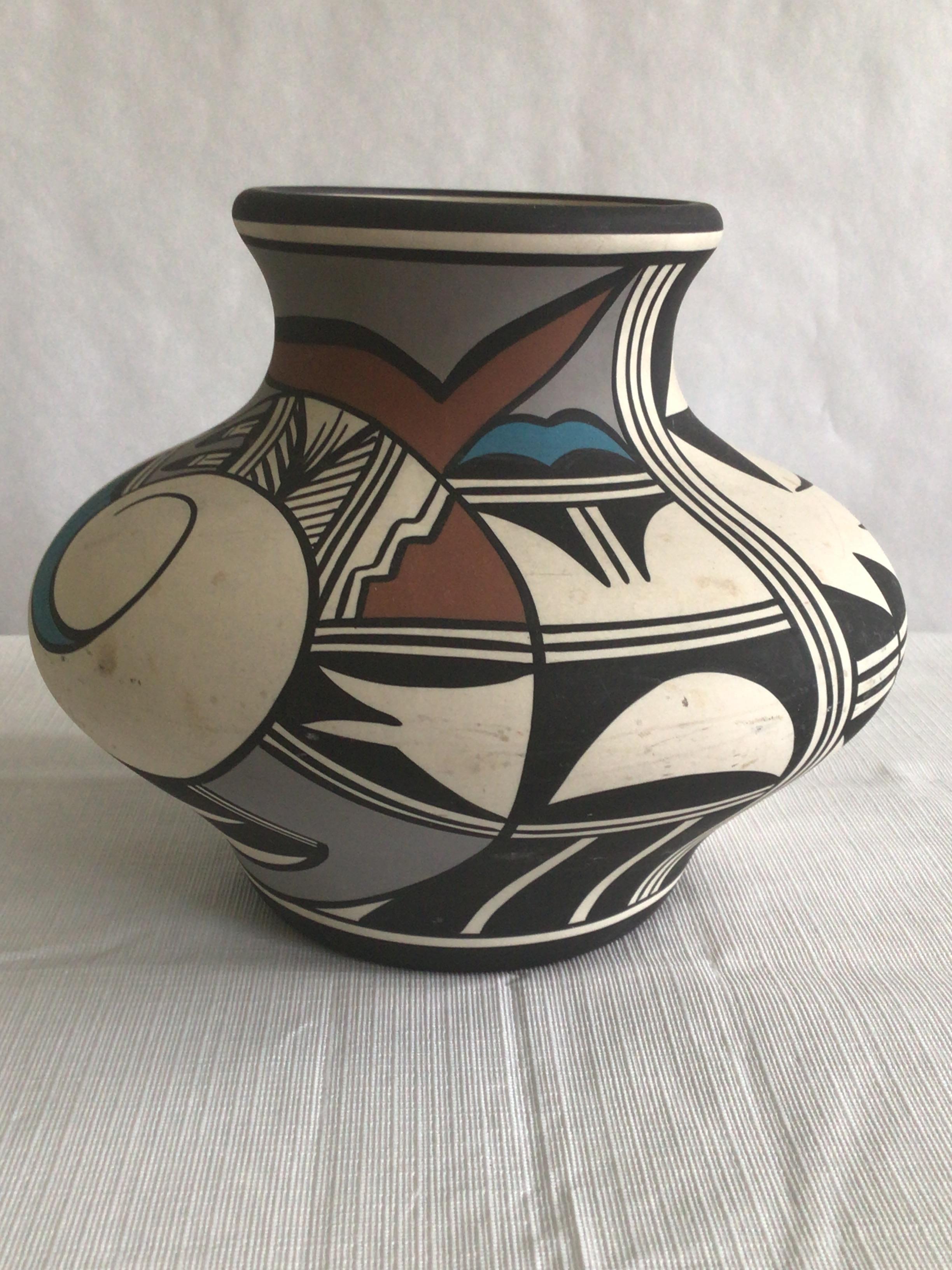 1970s Hand-Painted Native American Vase decorated with intricate geometric designs and natural pigment paints of black, brown, blue and grey on white clay. It is handmade from native clay, and pit fired in the traditional fashion.
Signed HapiBird