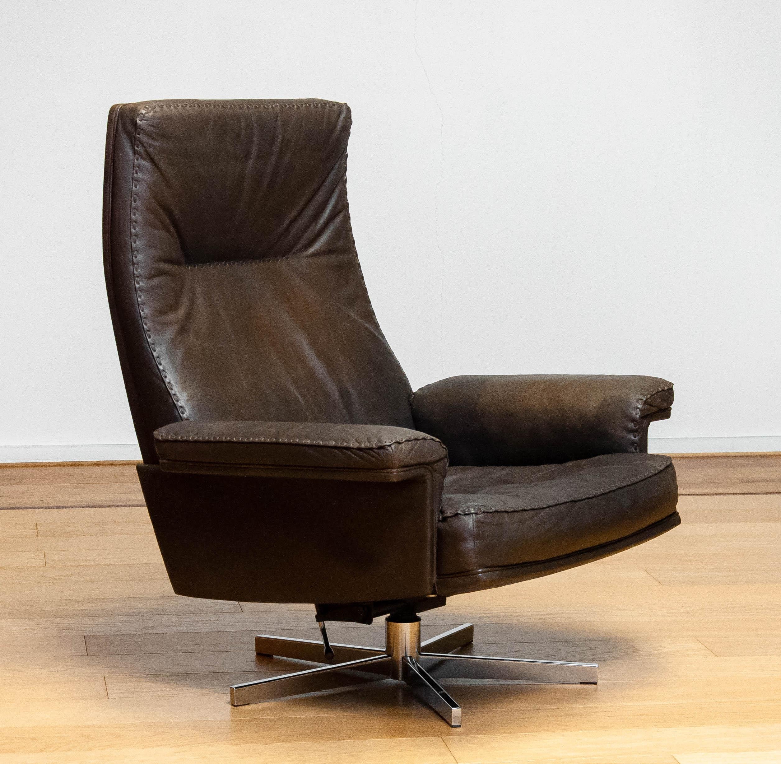Very comfortable swivel / lounge chair in brown leather with thick stitches made by the Swiss company De Sede and designed by Robert Haussmann.. The chair has beside the swivel also a adjustable rocking option true a torsion spring integrated in the