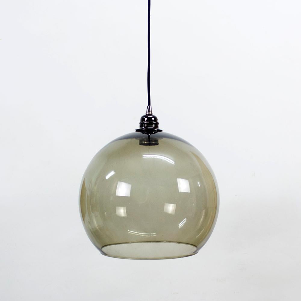 These ceiling pendents are Space Age meets Mid-Century Modern design and feature a large hand blown glass globe shade. The unique globe shade is a grey tinted color and showcases a single bulb on the inside. These pendents are perfect hung singly or