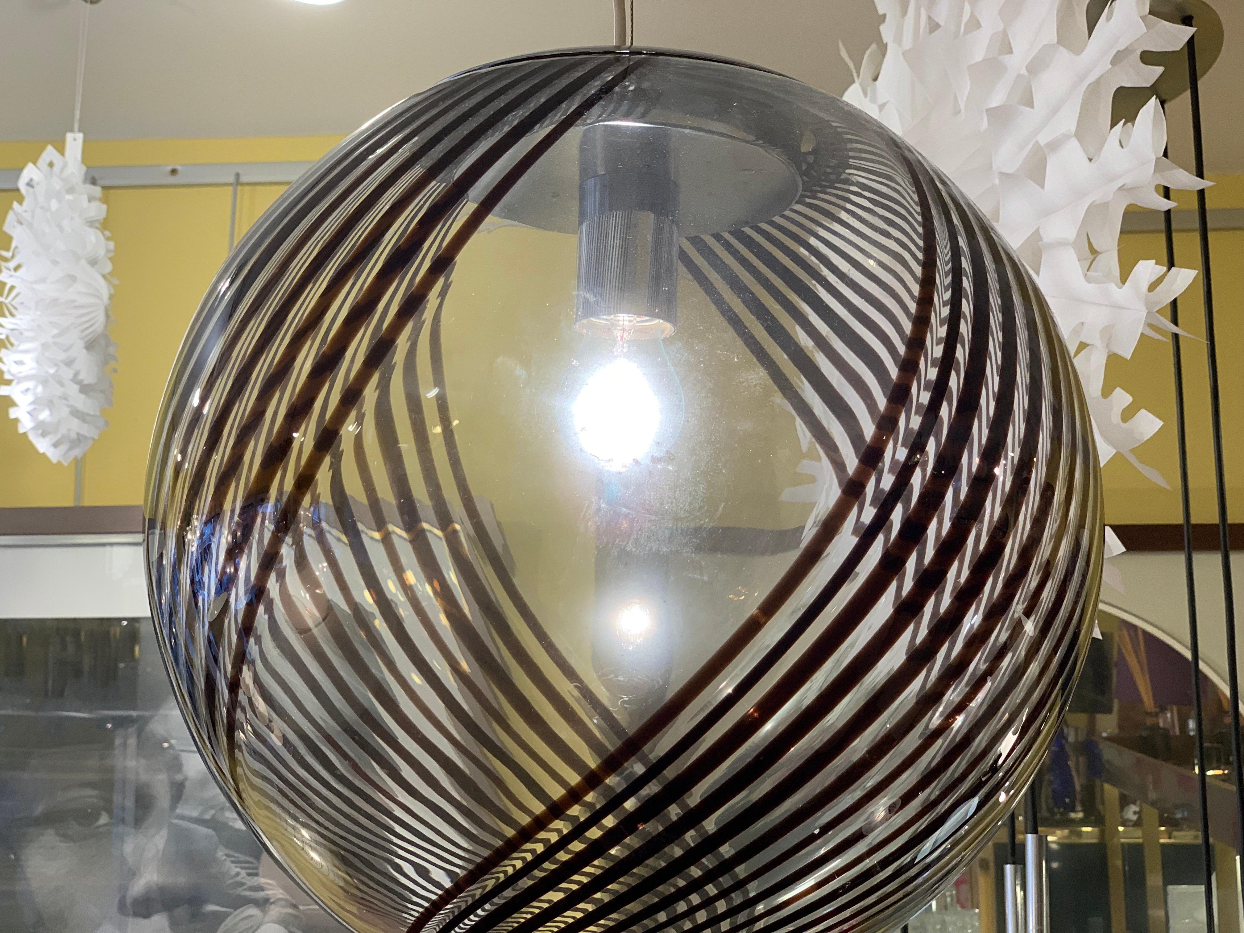 An Italian, Murano, 1970s, Venini style, beautiful, hand blown, glass globe pendant light. A stunning black swirled pattern runs over the surface of the clear glass globe. The lights hangs from its original chrome mount fitting. The pendant light is