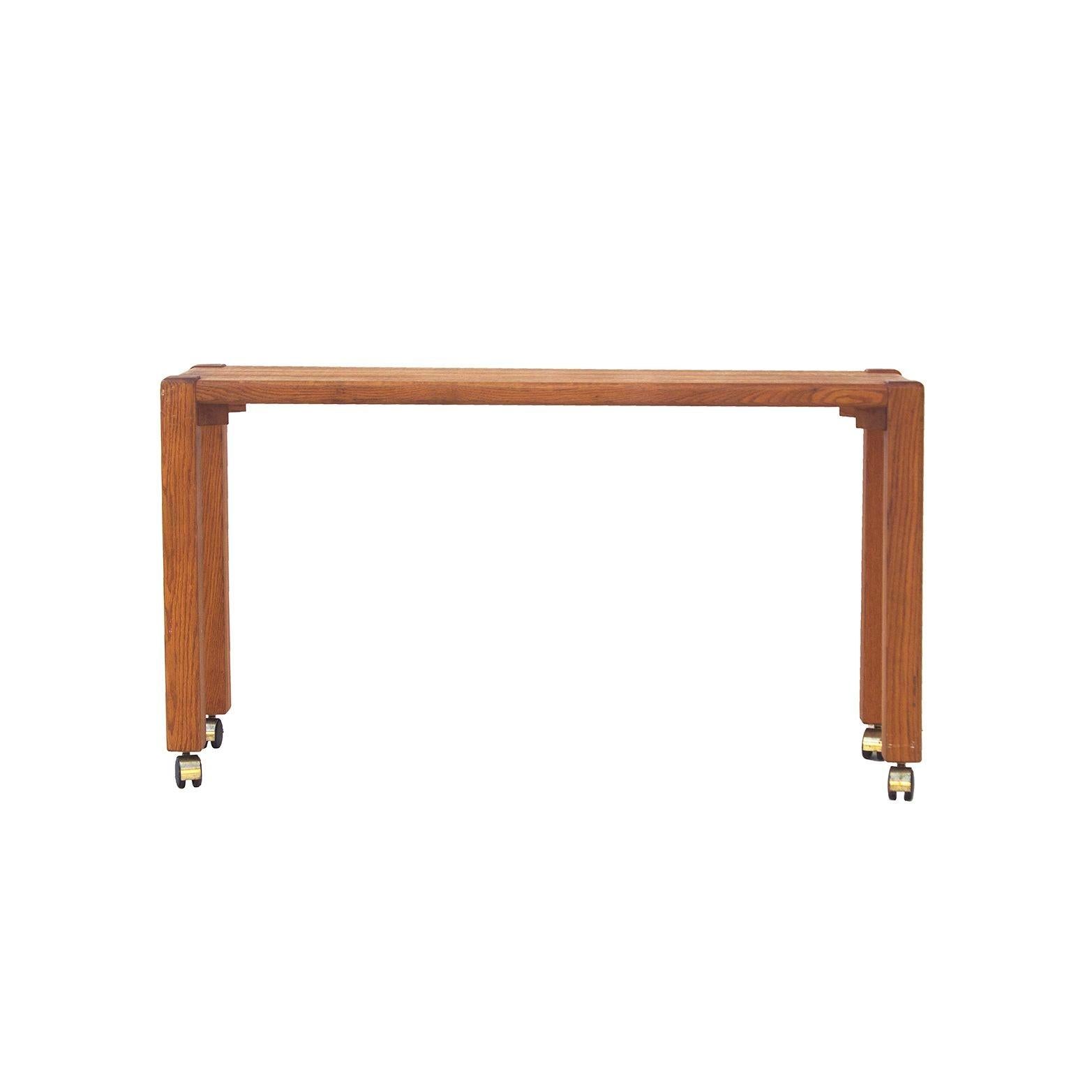 USA, 1970s
Handmade solid oak console table with interesting joinery features. Chunky legs at each of four corners offer visual interest. Currently on casters, which could be removed for a more organic look. Slimmer than most consoles at only 14.25