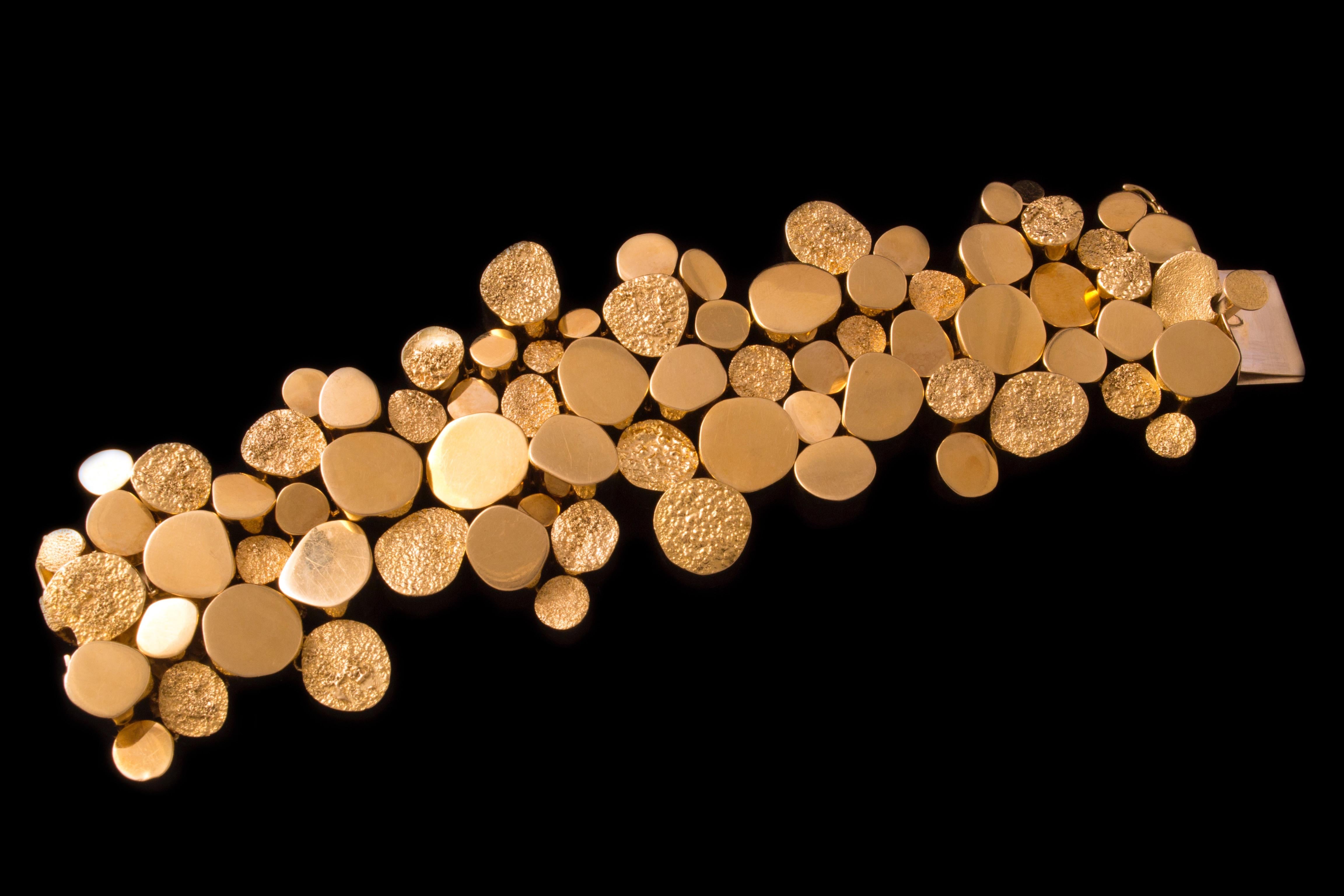 A textured and polished 18 karat gold riveted bracelet, unsigned, c. 1970. Comprised of handmade, riveted sections of textured and polished yellow gold.  Bracelet measures 7.2