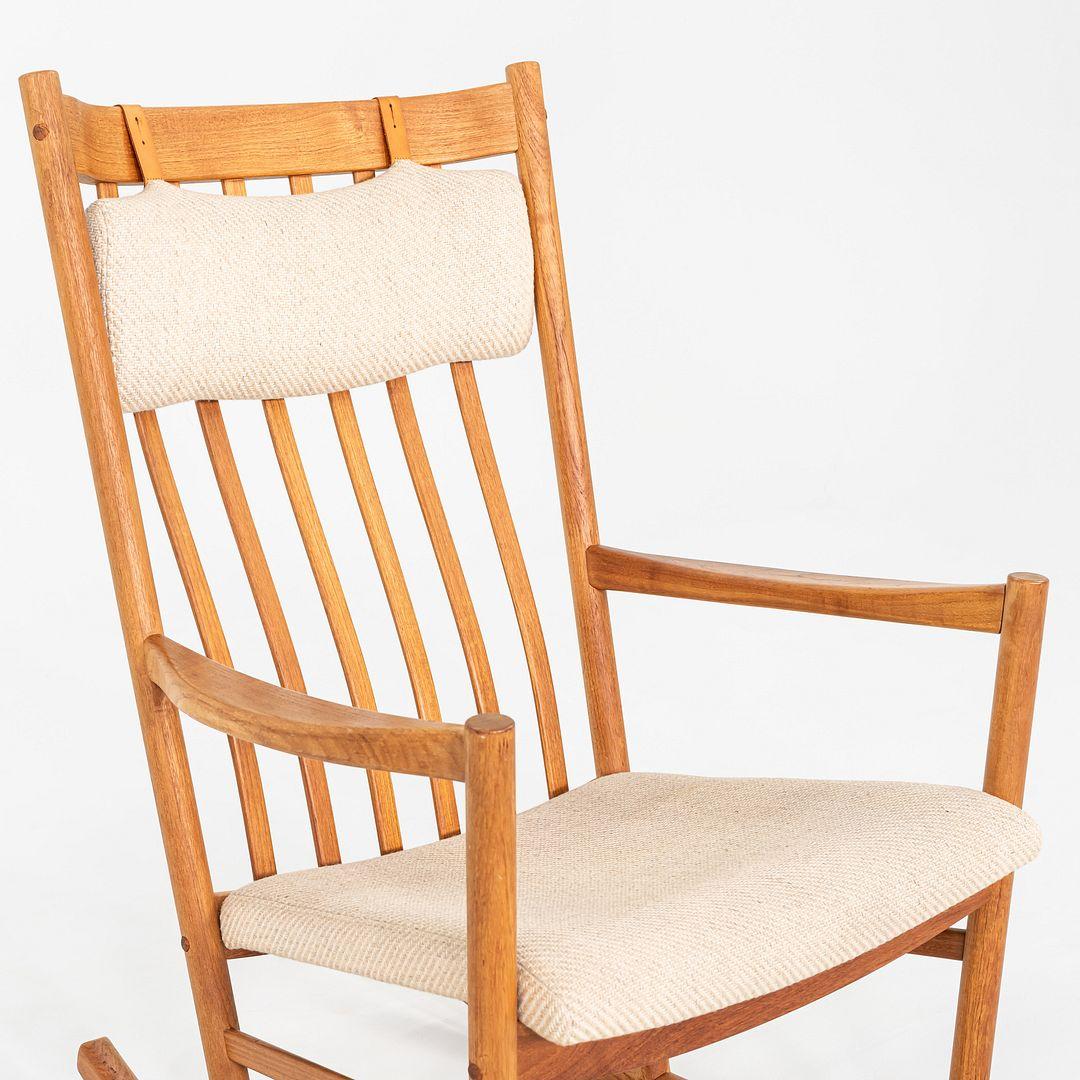 Questa è una sedia a dondolo in teak, disegnata da Hans Wegner per Tarm Stole, in Danimarca. Questo esempio risale agli anni '70. La struttura della sedia è in teak, mentre la seduta e lo schienale sono rivestiti in un tessuto neutro color marrone