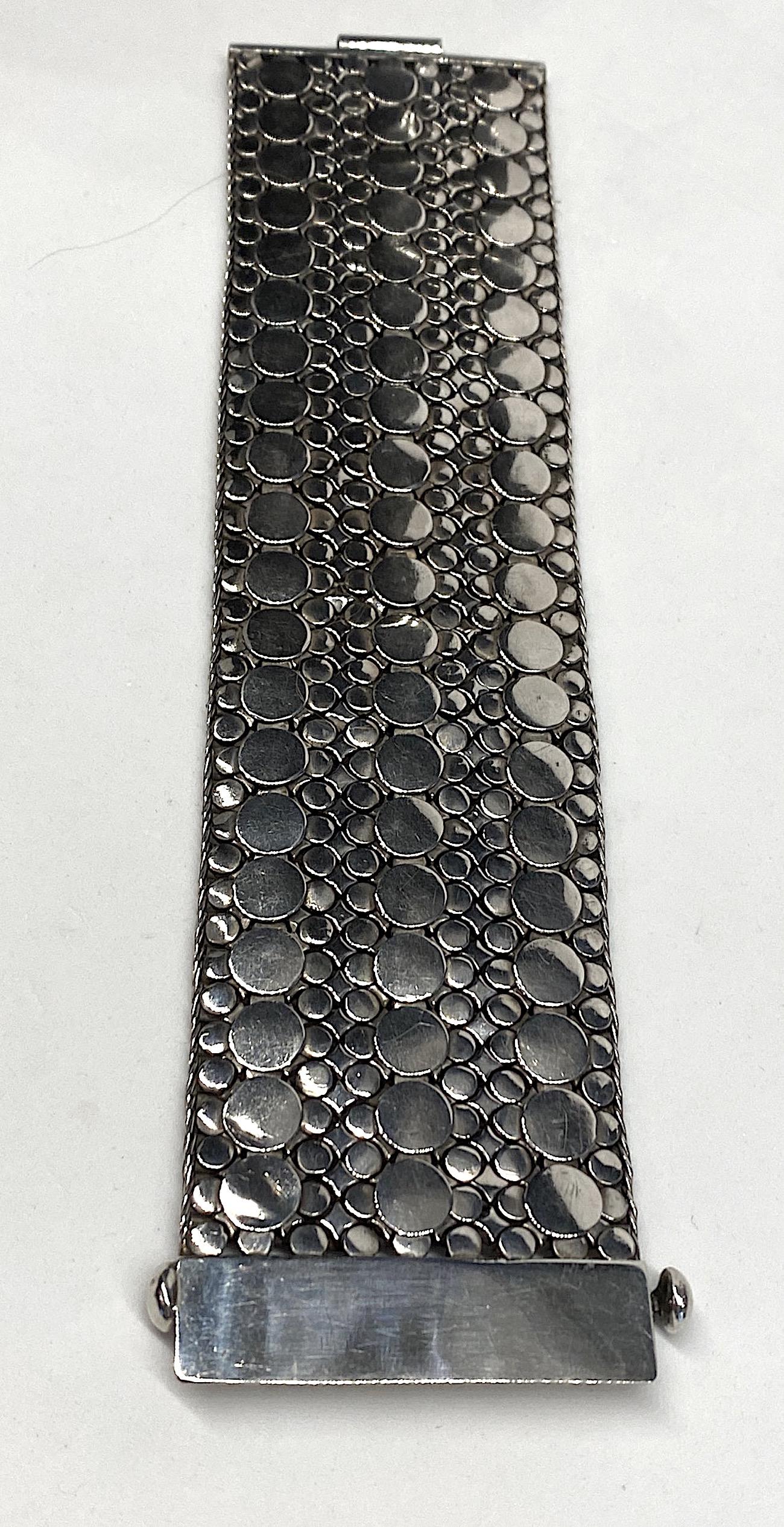A very impressive sterling silver hand made for a man or woman. The back layer of the bracelet is made up of 1/8 inch wide links woven together finishing white the top layer is made up of applied large and small disks. It is 8.75 inches long and