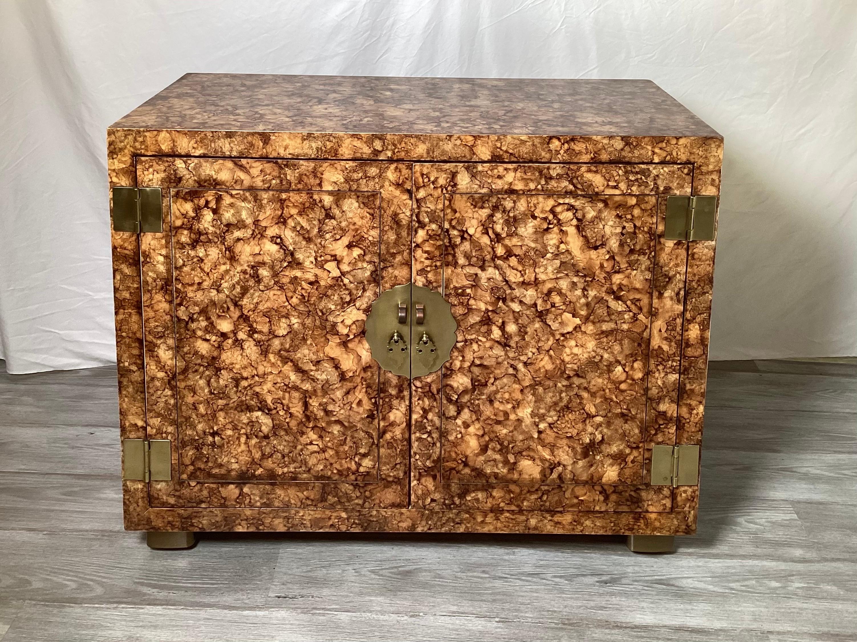 A Classic 1970's campaign style doored chest by Henredon.  The chic finish with a faux tortoise pattern.  The doors open to reveal a drawer with shelf.  The antiqued brass hardware in the campaign class style   