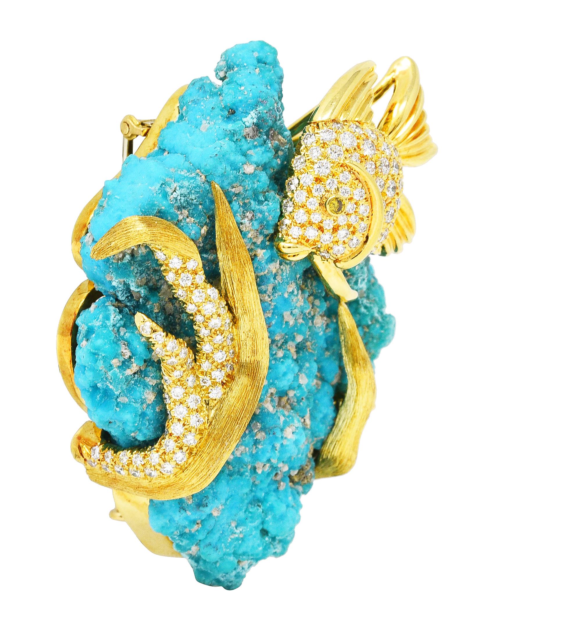Substantial brooch features turquoise aggregate wrapped in gold seaweed tendrils and a fish. Turquoise is opaque greenish blue with mineral crystal inclusions throughout including golden pyrite. Accented by a triad of round brilliant cut diamonds