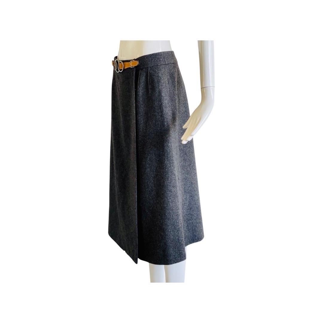 Superbe jupe portefeuille en laine lourde Hermès des années 1970, avec une ceinture de couleur havane sur le devant et trois boucles circulaires entrecroisées. La jupe se ferme à l'aide d'un crochet et de boutons internes. Entièrement doublé en