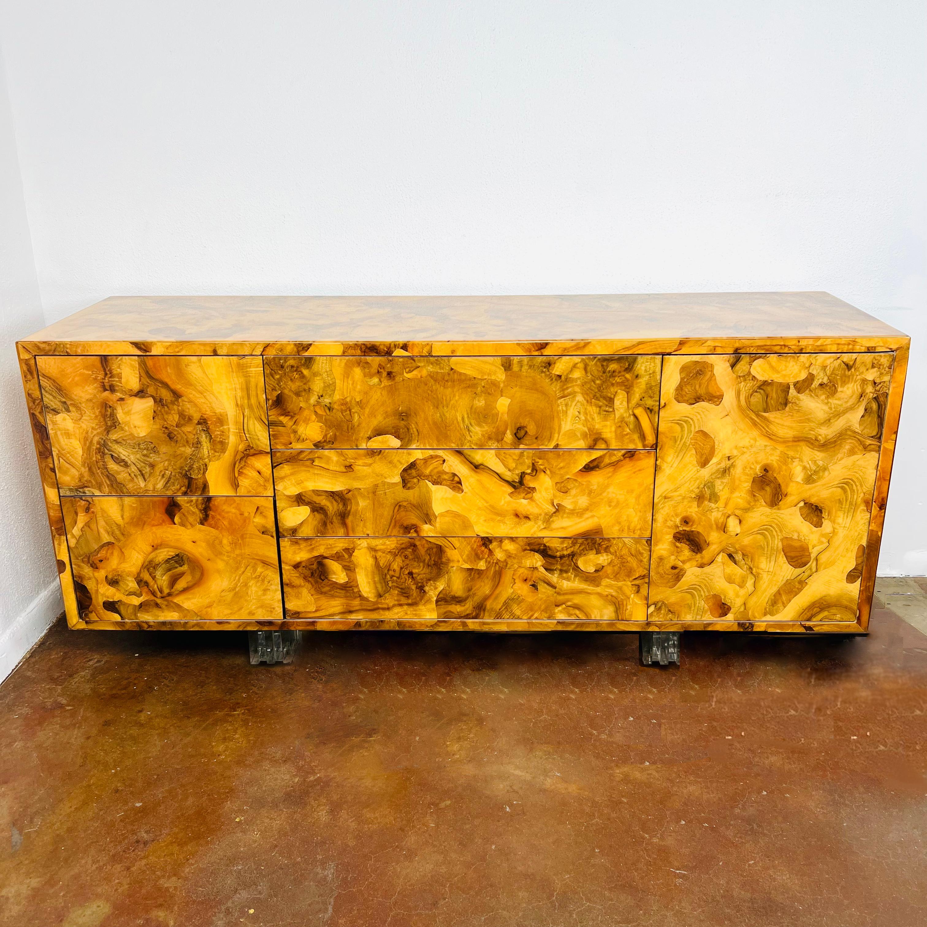 Fabulous, unique 1970s burl wood credenza on stacked lucite legs. An adjustable interior shelf provides storage space, while cabinet faces showcase unique and naturally occurring patterns in the wood. Form plus function equals fabulously cool.