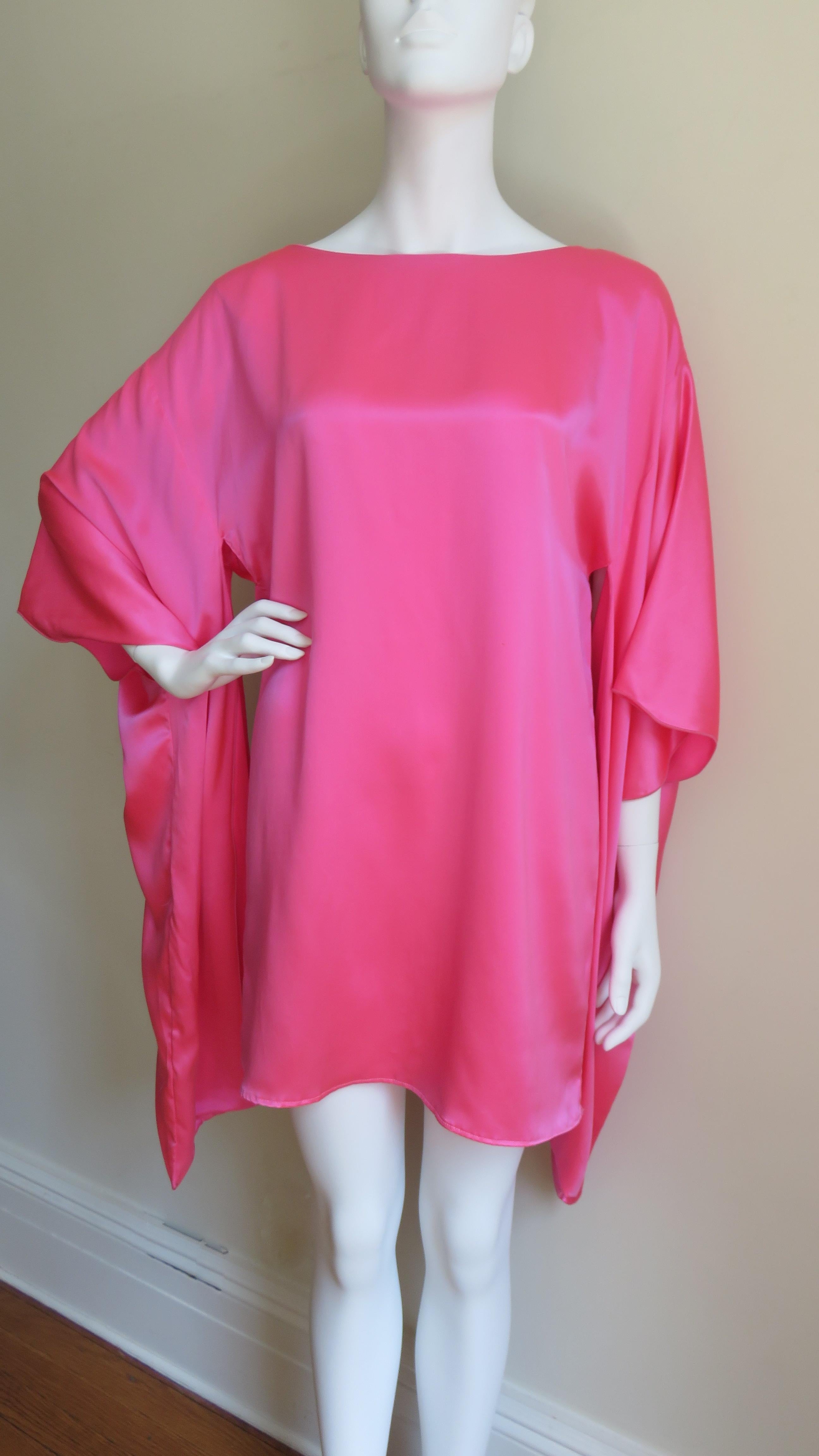 An incredible vibrant pink silk charmeuse dress from Holly Harp.  It has a wider crew neckline with a keyhole back and a self covered button/loop above it.  It's cut straight from the shoulders with amazing elbow length sleeves with long drapes open