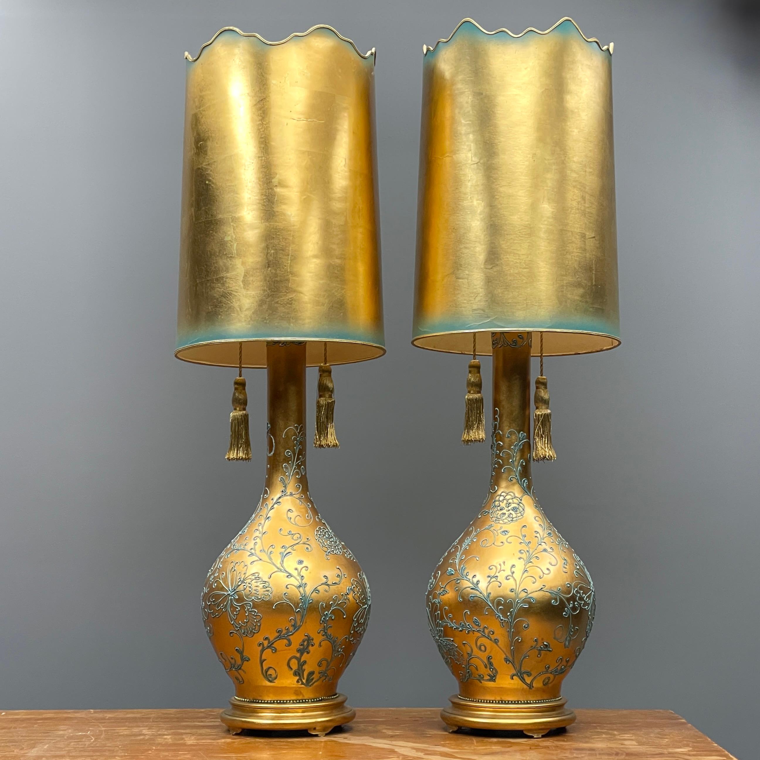 A pair of very large vintage Hollywood Regency style table lamps, featuring gold gilt and laced light icy teal accents, including the matching scalloped shades and decorative tassels. In the style of designer brand such as those of James Mont or