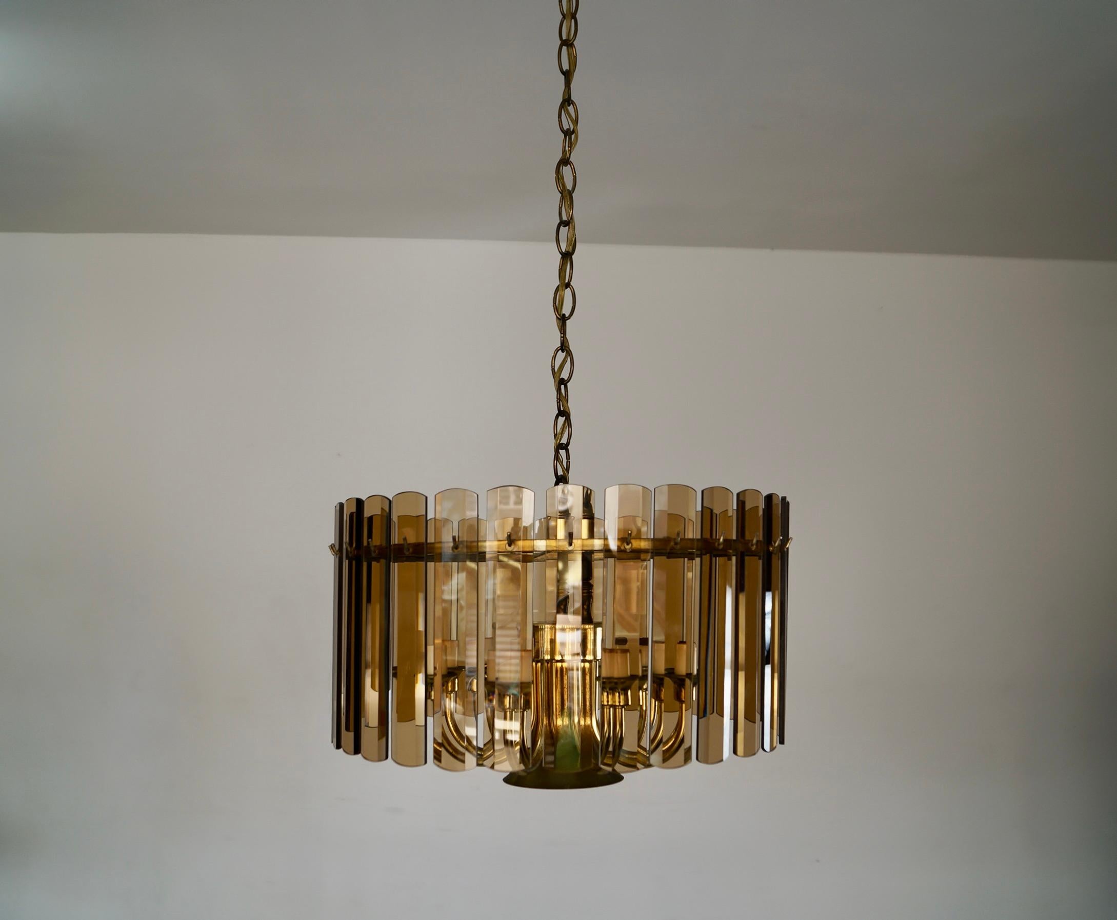 Lampadario vintage Midcentury Modern in vendita. Si tratta di una bellissima lampada in ottone, con vetro scuro fumé appeso a ganci in ottone. Il vetro è smussato e in ottime condizioni. L'ottone presenta una patina vintage. Ha otto luci a braccio
