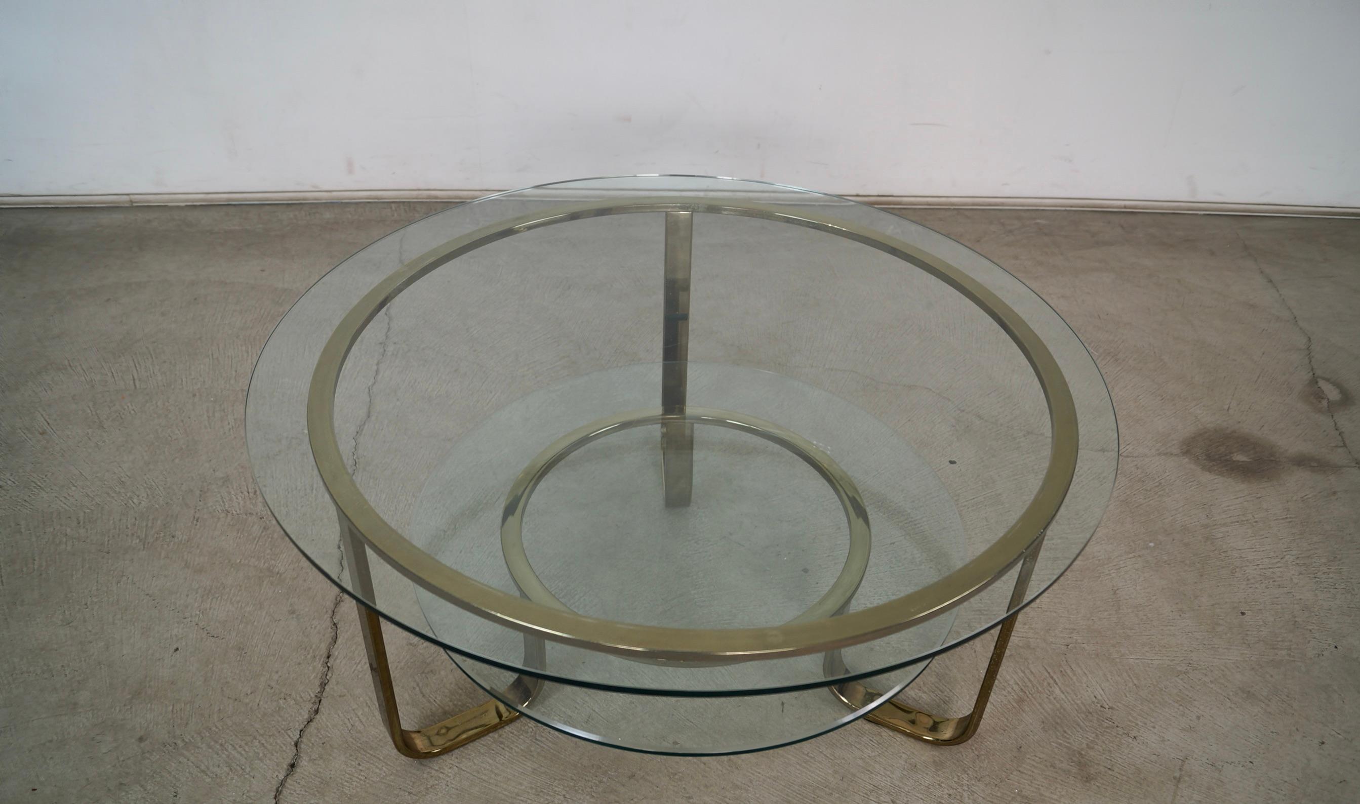 Tavolino da caffè Art Deco vintage degli anni '70 in vendita. Ha una base in ottone con un piano in vetro e un ripiano in vetro al di sotto. L'ottone presenta un'usura d'epoca, mentre il vetro è in ottime condizioni, senza scheggiature o crepe. Il