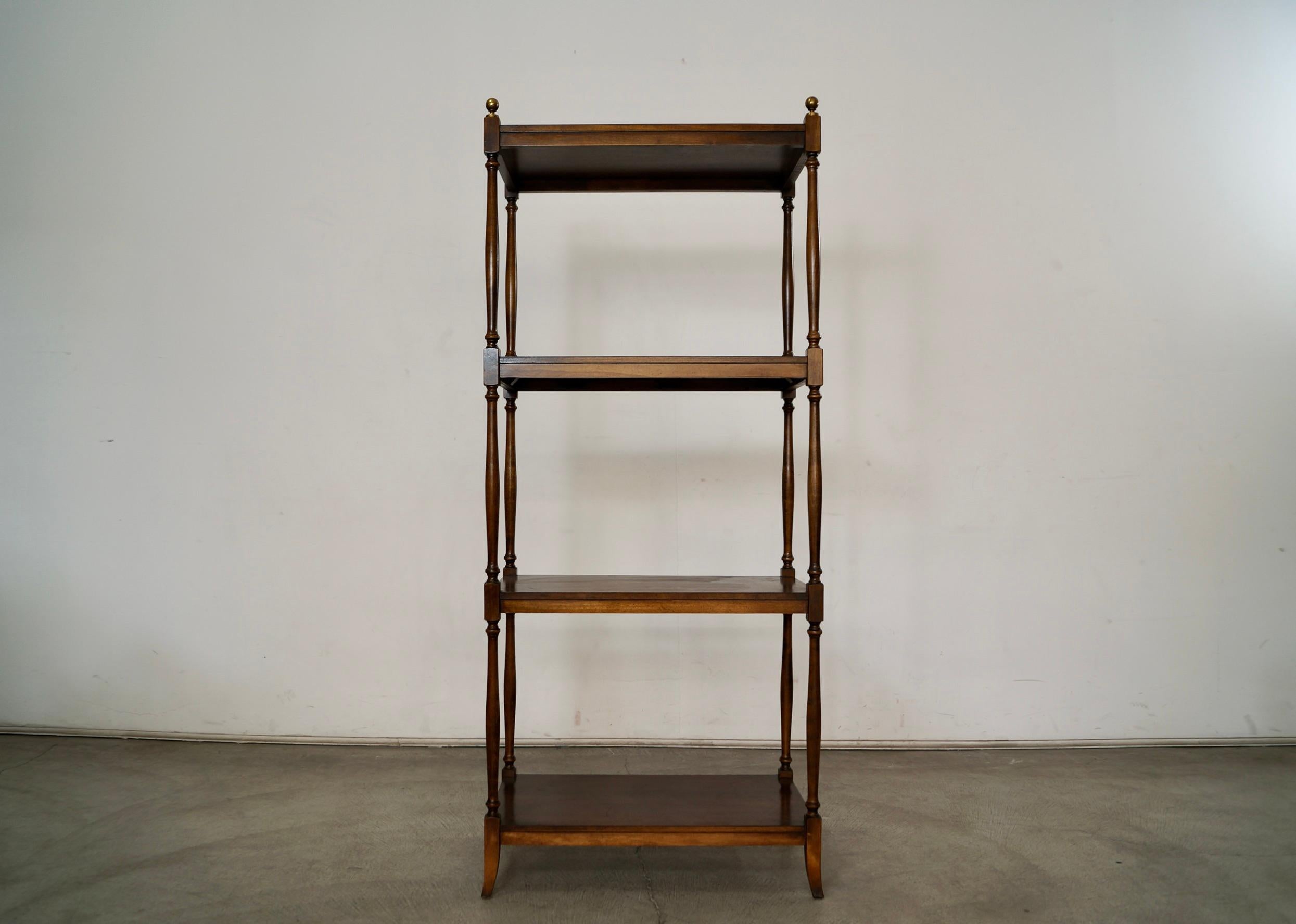 Vintage 1970's bookshelf for sale. Manufactured by the high-quality company Brandt, and made in Maryland back in the 70's. It's made of wood with a walnut finish, and has solid brass ball caps at the tips on the top. It's in excellent condition, and