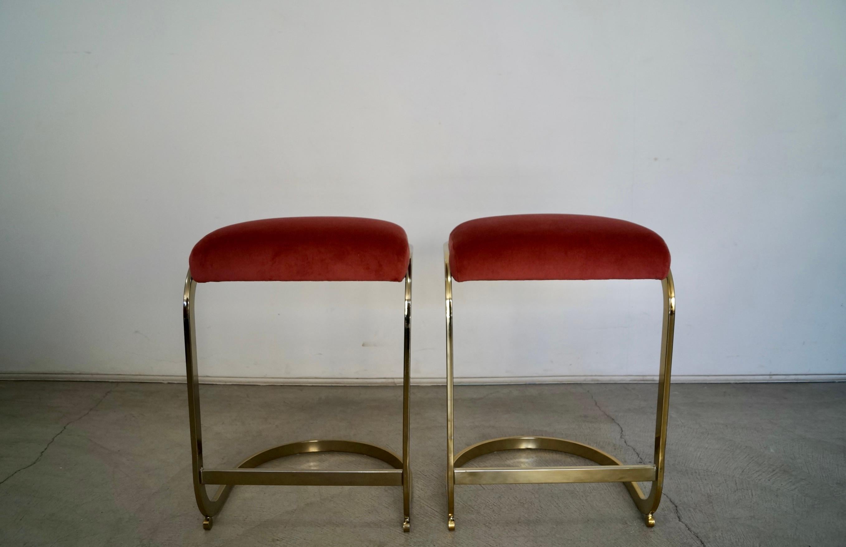 Pair of vintage 1970s Mid-Century Modern cantilever stools for sale. These have been professionally reupholstered in new pink velvet and foam. They have an elegant design in the manner of Milo Baughman designs. They have a cantilever frame in brass