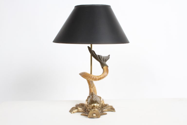 Hollywood Regency Chapman Dolphin fish lamp base with brass head and tail, with faux ram horn body. Sold with vintage black shade with spot oil interior. Two Chapman labels, one marked 1972. In fine condition on light scuffs to shade, tested. Shade