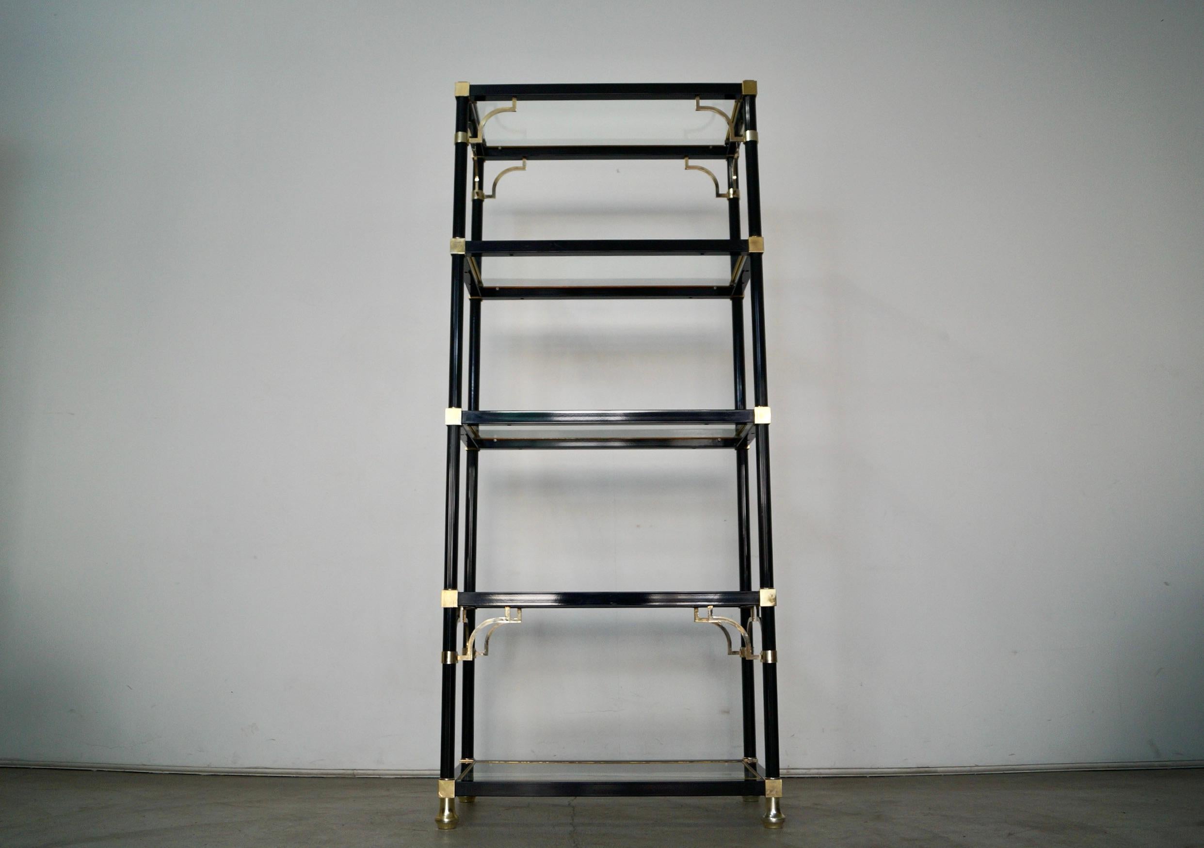 Gorgeous vintage Mid century Modern shelving unit for sale. Manufactured in the 1970's, and very well made. It's made of aluminum and metal, and has brass accents and details. It has five glass shelves that go inserted into the metal frame, and the