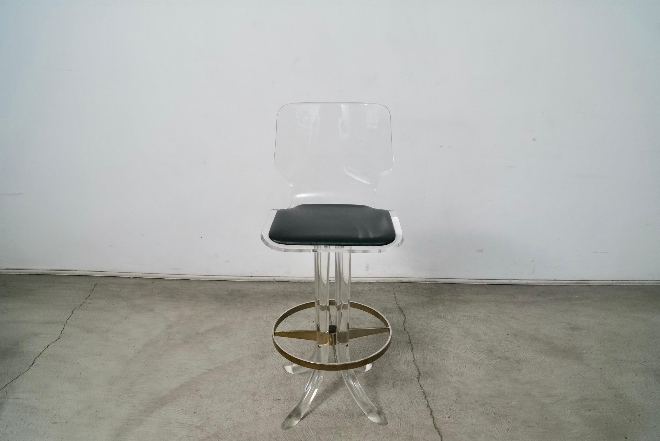 Vintage Midcentury Modern barstool for sale. Manufactured by Hill Furniture, and still has the original label attached underneath. Made of thick solid lucite with a sculptural base and four lucite flared legs. The stool swivels, and is very