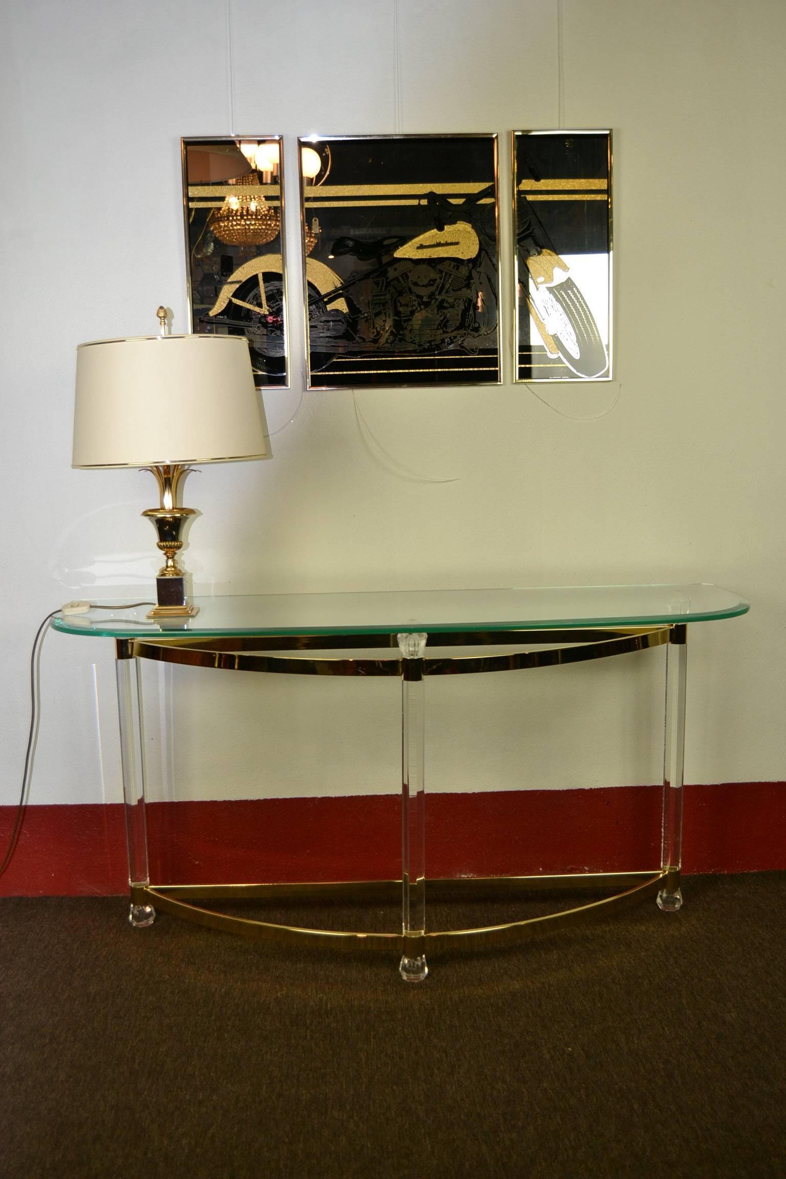 Elegant 1970s Lucite Console Table or Side Table with Glass Top.  
This Table in Hollywood Regency Style 
is made of Clear Perspex -  Plexiglass with Brass Feet , 
and has a Rounded Facet Glass Top. 
This Stylish Table is in good vintage condition.
