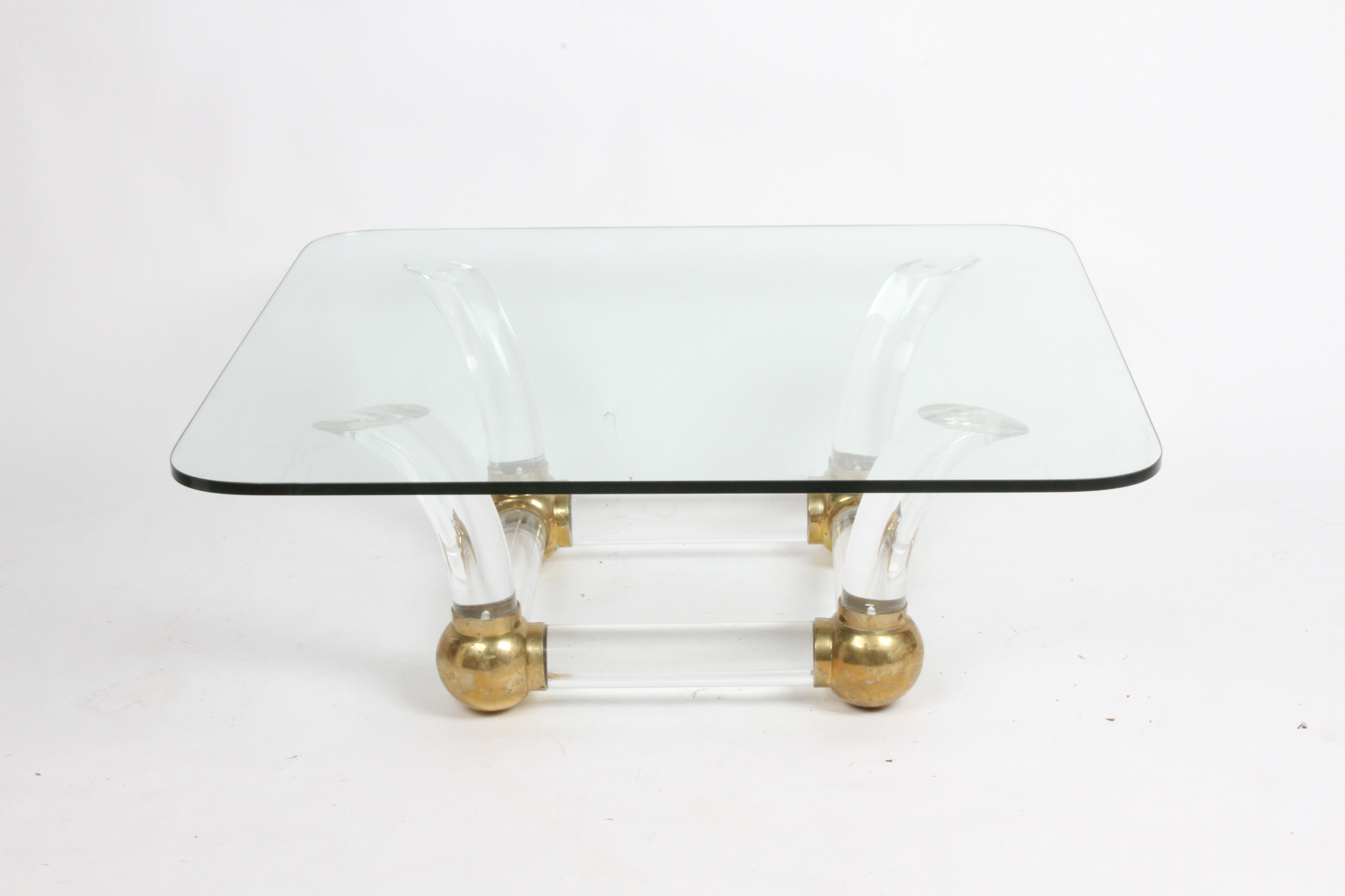 70s Hollywood Regency coffee table with thick Lucite tusks connected to large brass balls with glass top, in the style of Karl Springer. If fine condition, light scratches to glass to be expected, patina to brass. Need to reconfirm table height.