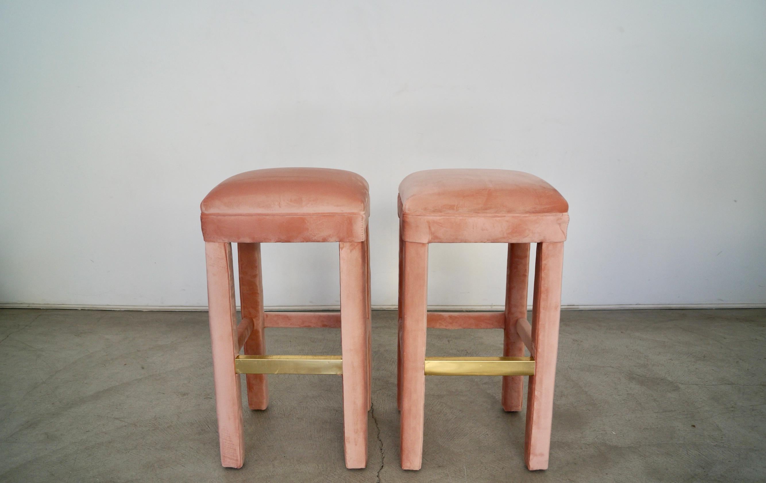 Vintage 1970's Hollywood Regency parsons bar stools for sale. These were reupholstered in pink velvet, and are fully upholstered. The hey have brass footrest. They are really solid and well made, and have springs on the seats. These are original