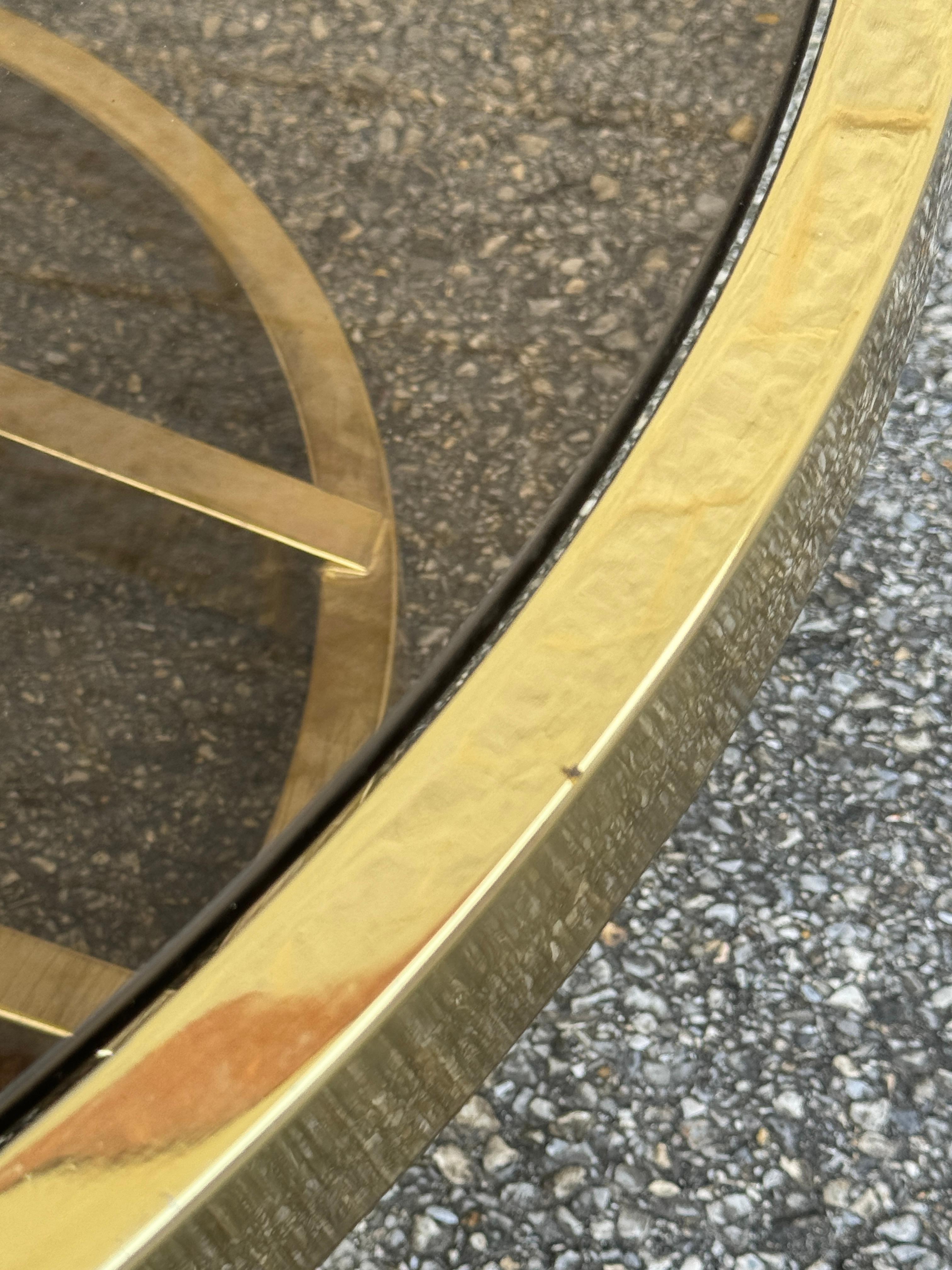 Table basse ronde en porte-à-faux de style Hollywood Regency en finition laiton avec plateau amovible en verre fumé.
