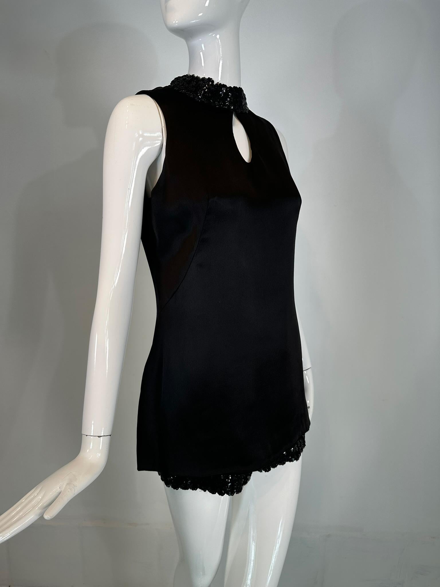 1970s hot pants set black satin & black sequins key hole tunic top & short shorts. The sleeveless tunic top has a band neck that is sewn with black sequins, there is a center upper front key hole opening.  The top is below hip length and has side