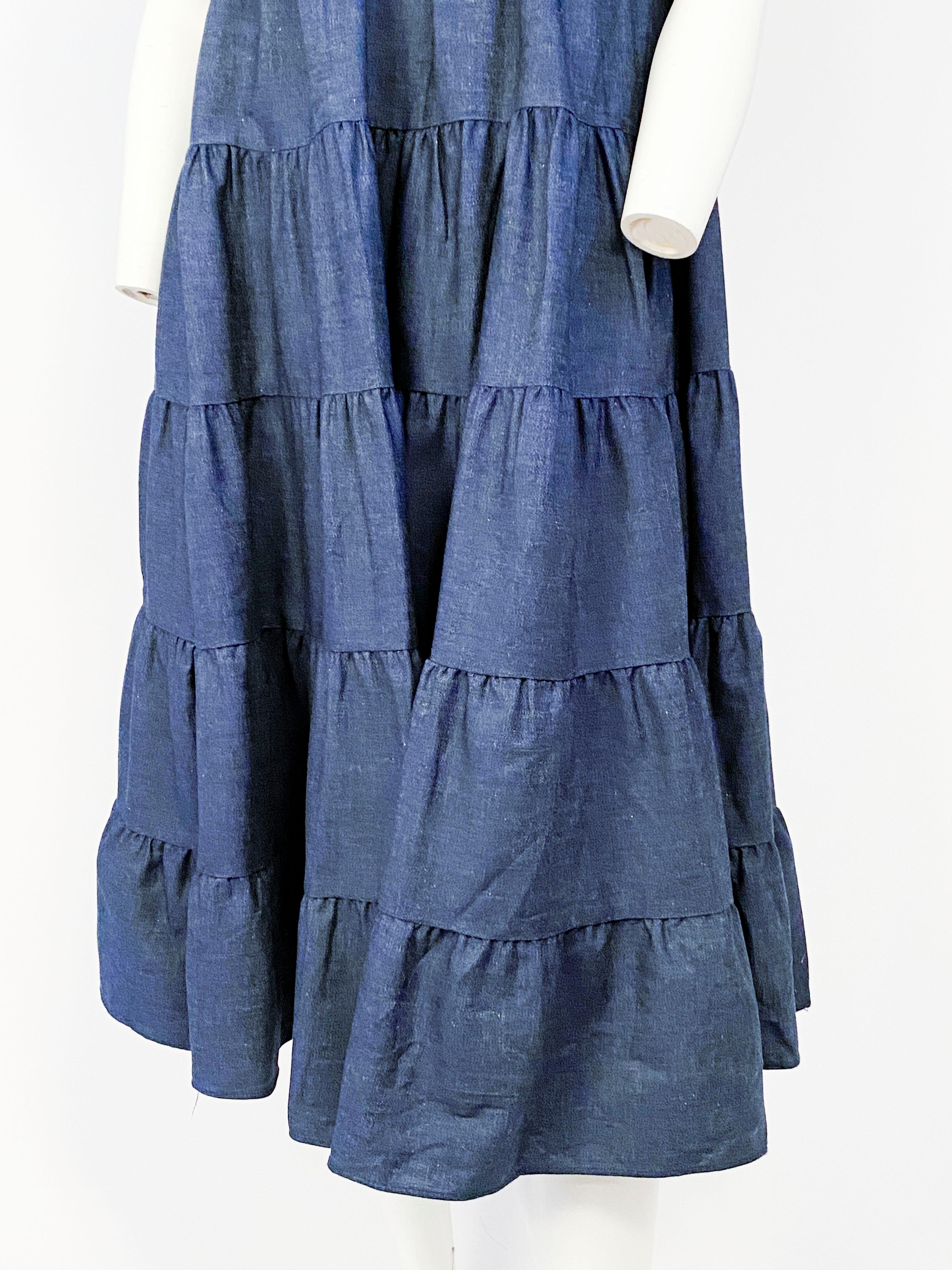 1970s denim dress with layered rows of ruffled denim along the high empire-waisted skirt. The scoop neckline accentuates the full puffed short sleeves. 