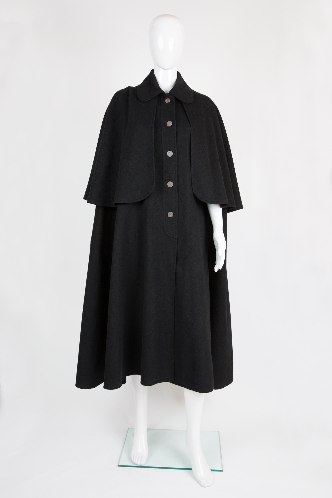 Iconic 1970s YSL Yves Saint Laurent black wool cape coat featuring a front silver tone button opening, inside slits to pass arms.
In good vintage condition. Made in France. 
Label size 38fr/US6 /UK10
We guarantee you will receive this gorgeous item