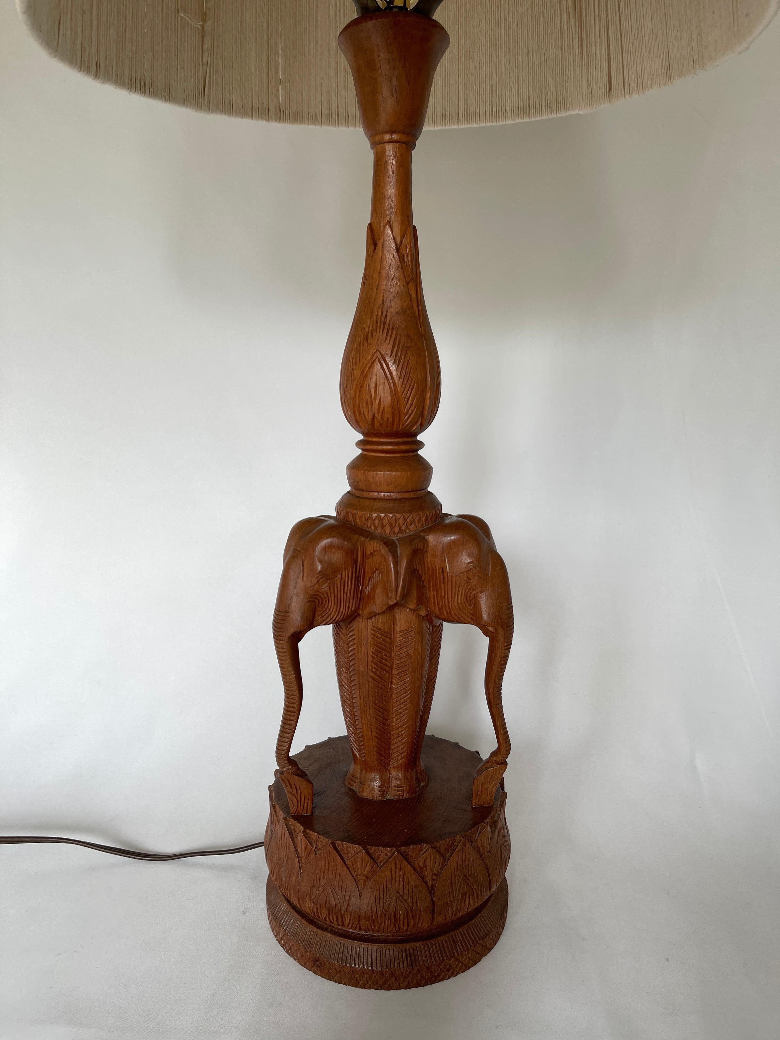 Indian hand carved teakwood lamp with three elephants on lotus flower base. Features original Haitian cotton string lampshade. 
Lamp height including harp and lampshade 31.5