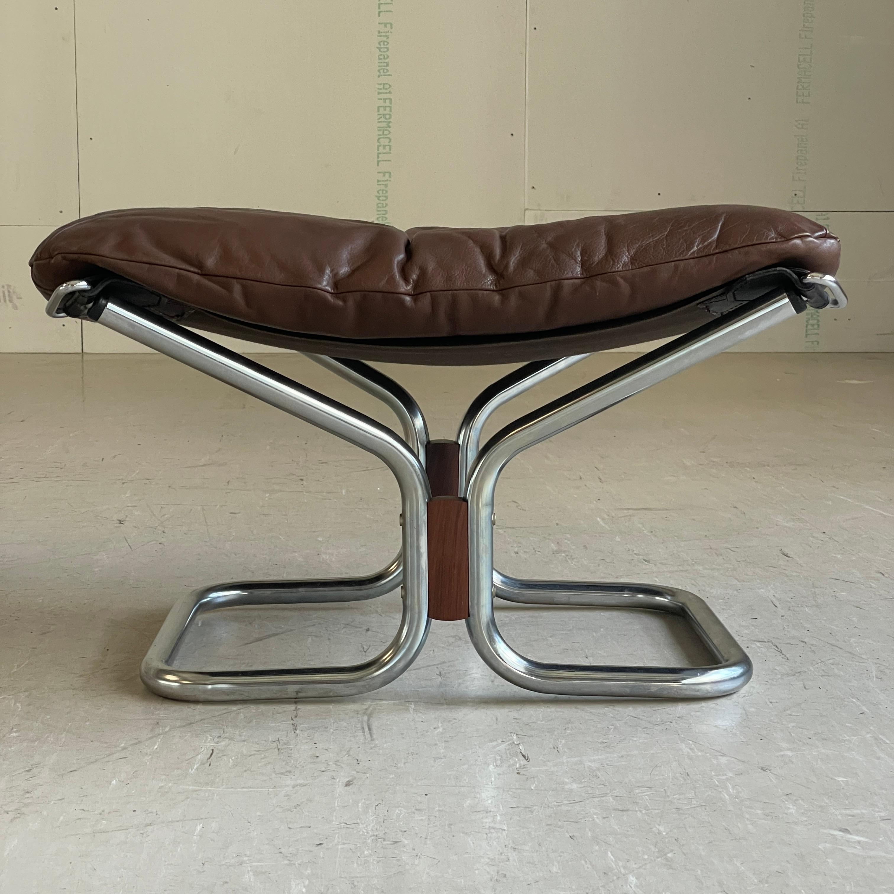 1970's Ingmar Relling leather ottoman. Compliments the 'Wing' chair produced by Westnova, Norway. Tubular chromed metal base with rosewood accents. Sling seat support with removable brown leather seat cushion.
Leather in excellent condition with