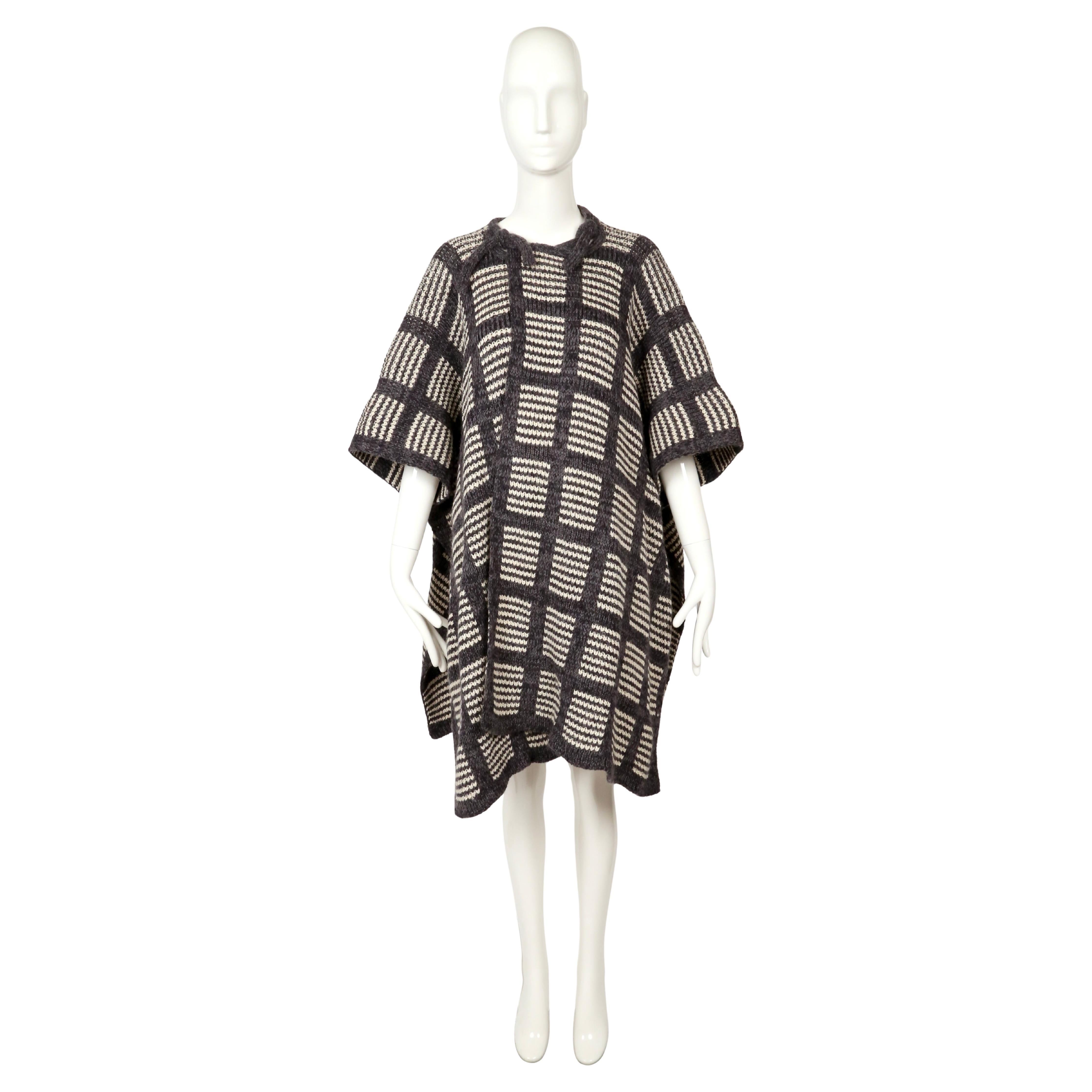 Eccezionalmente raro cappotto in maglia di Issey Miyake degli anni '70, di colore antracite e avorio. Realizzato a mano con un audace motivo a quadri a finestre, questo pezzo incarna la prima sperimentazione di Miyake con la maglieria e la struttura