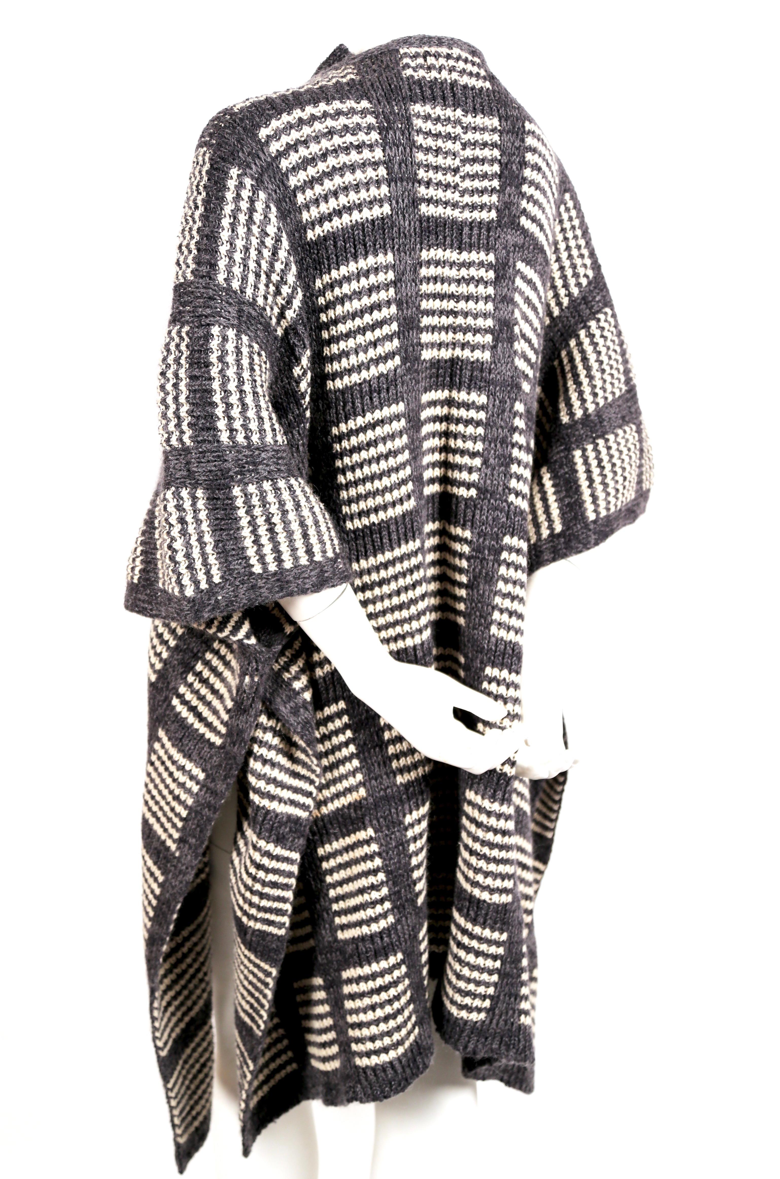 Sehr seltener, grau-weißer Strickponcho-Cape-Mantel von Issey Miyake aus den 1970er Jahren. Größe S, passt aber durch den lockeren Schnitt vielen Größen. Krawatten im Nacken. Inhalt des Stoffes: 50% Wolle 30% Seide, 10% Acryl und 10% Nylon.