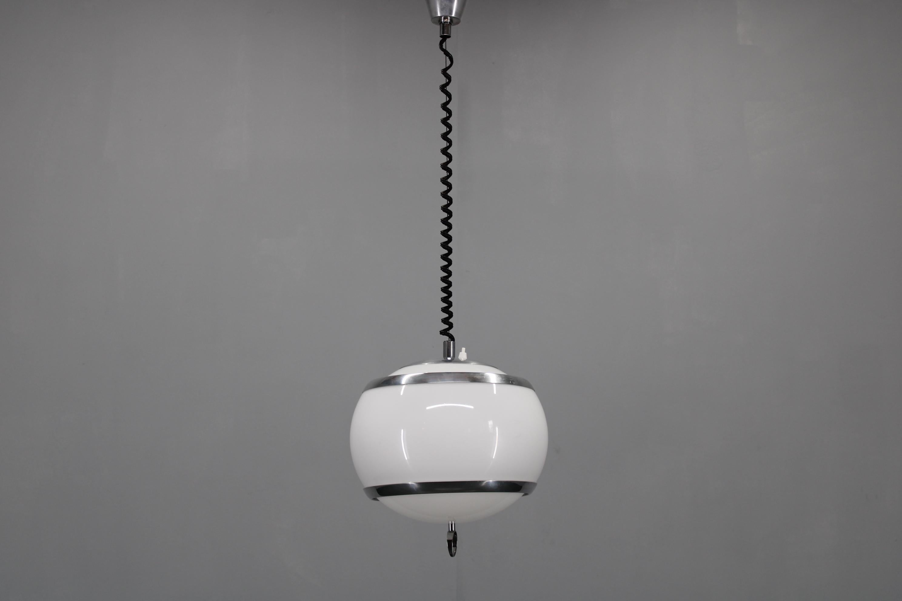 Autentica lampada a sospensione regolabile vintage, risalente agli anni '70, con un giocoso design sferico dell'era spaziale. La lampada presenta un globo in plastica bianca lucida accentuato da bande e dettagli in metallo cromato lucido. Il suo