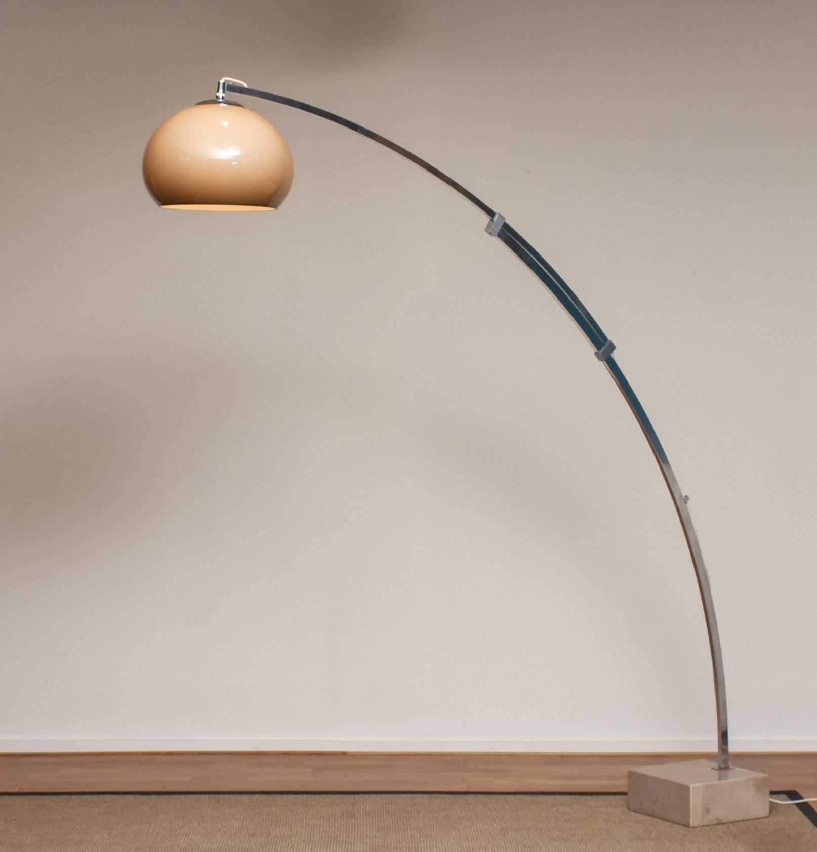 Iconique lampadaire à arc italien par Harvey Guzzini sur une base carrée en travertin:: le tout en bon état. L'abat-jour en polyester est également en bon état. Comprend une ampoule à vis de taille E27 / E28 et convient aussi bien à 230 qu'à 110