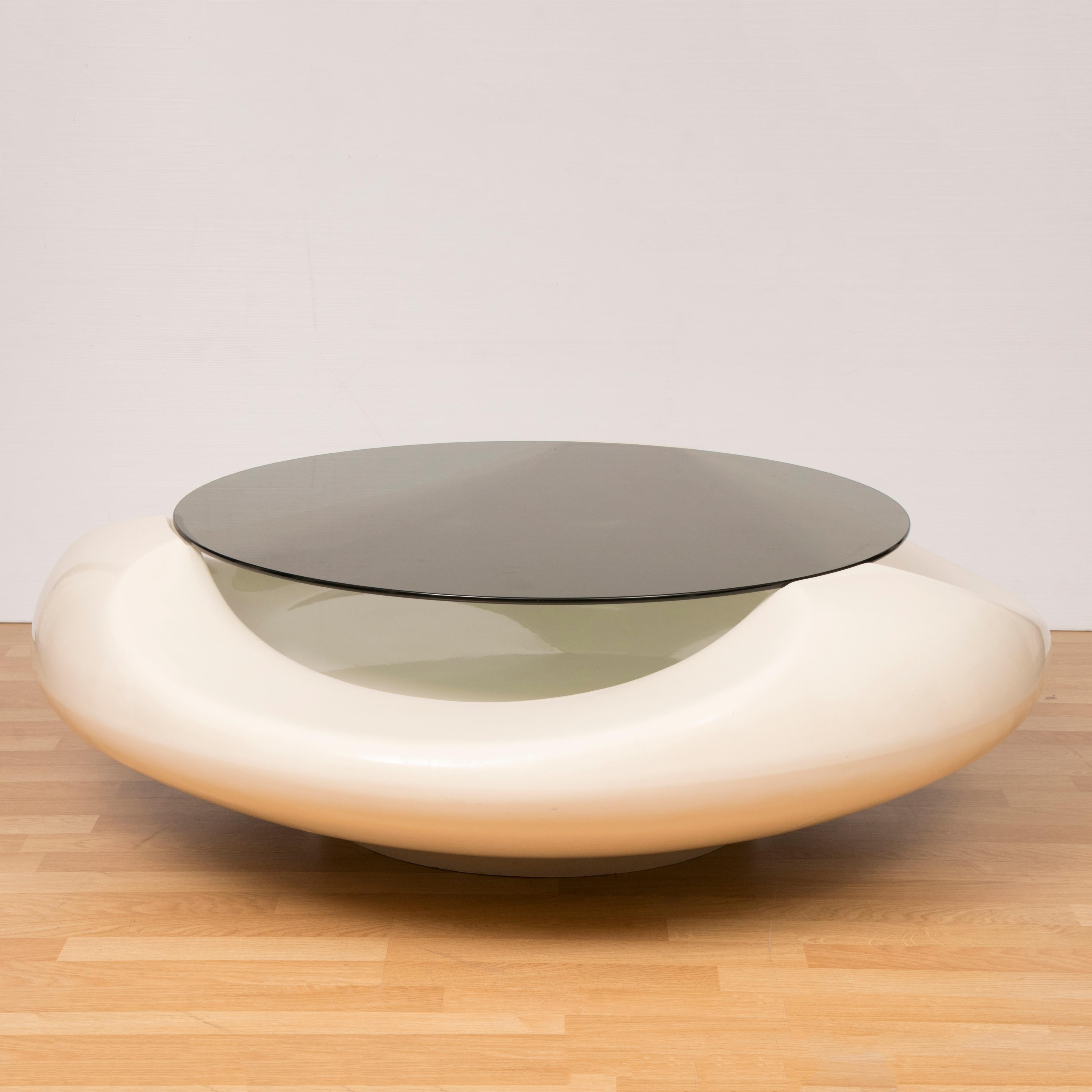 Large Italian 1970s space-age coffee table in the shape of a UFO. Designed and manufactured by Astarte Milano in Italy. This particular table is their larger version. Made of white fibreglass with a round smoked glass tabletop which sits in place on