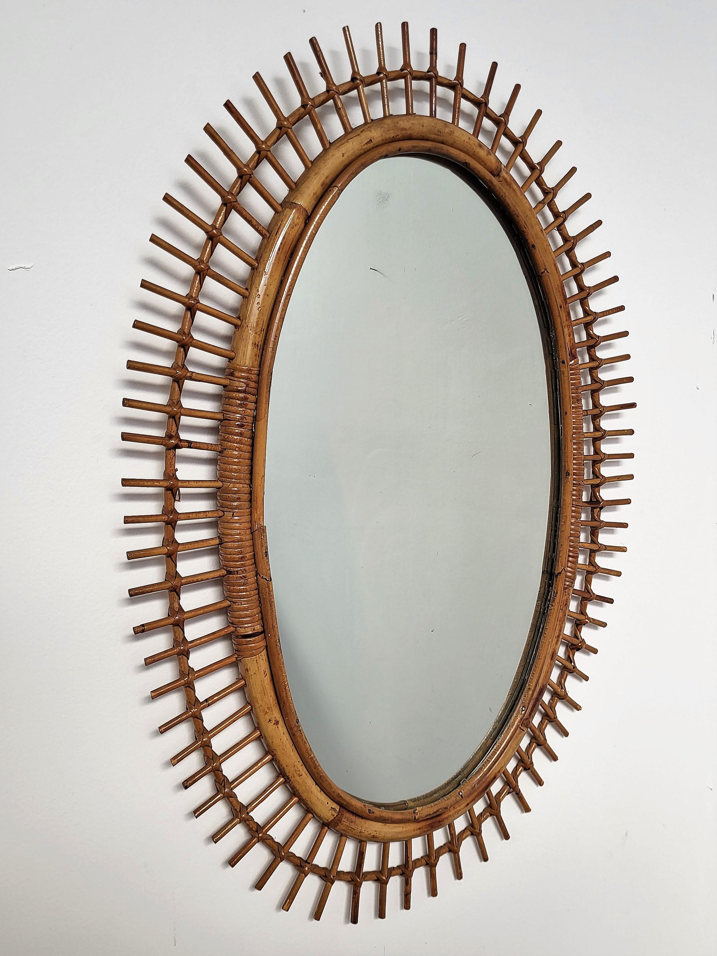 Beautiful 1970s Italian Mid-Century Modern oval shaped wall mirror made of rattan and bamboo. This charming piece is in the typical style of Franco Albini, Adrien Audoux and Vittorio Bonacina where the organic beauty of the woven materials is