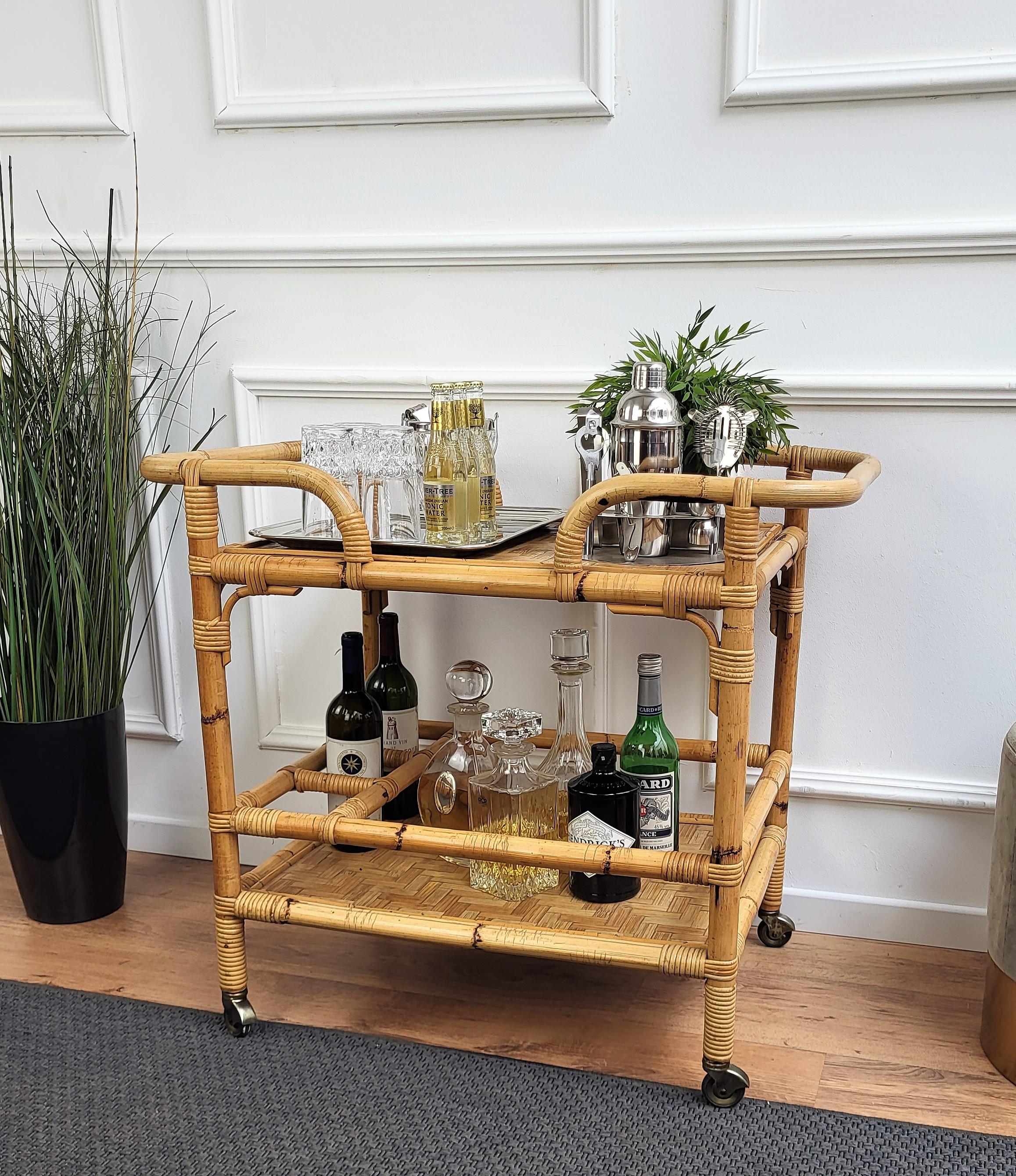 Beautiful 1970s Italian Mid-Century Modern serving bar cart trolley probably by the Italian Vittorio Bonacina featuring two levels, with the bottom one with three bottle holders. Made of rattan and bamboo. This charming piece is in the typical style