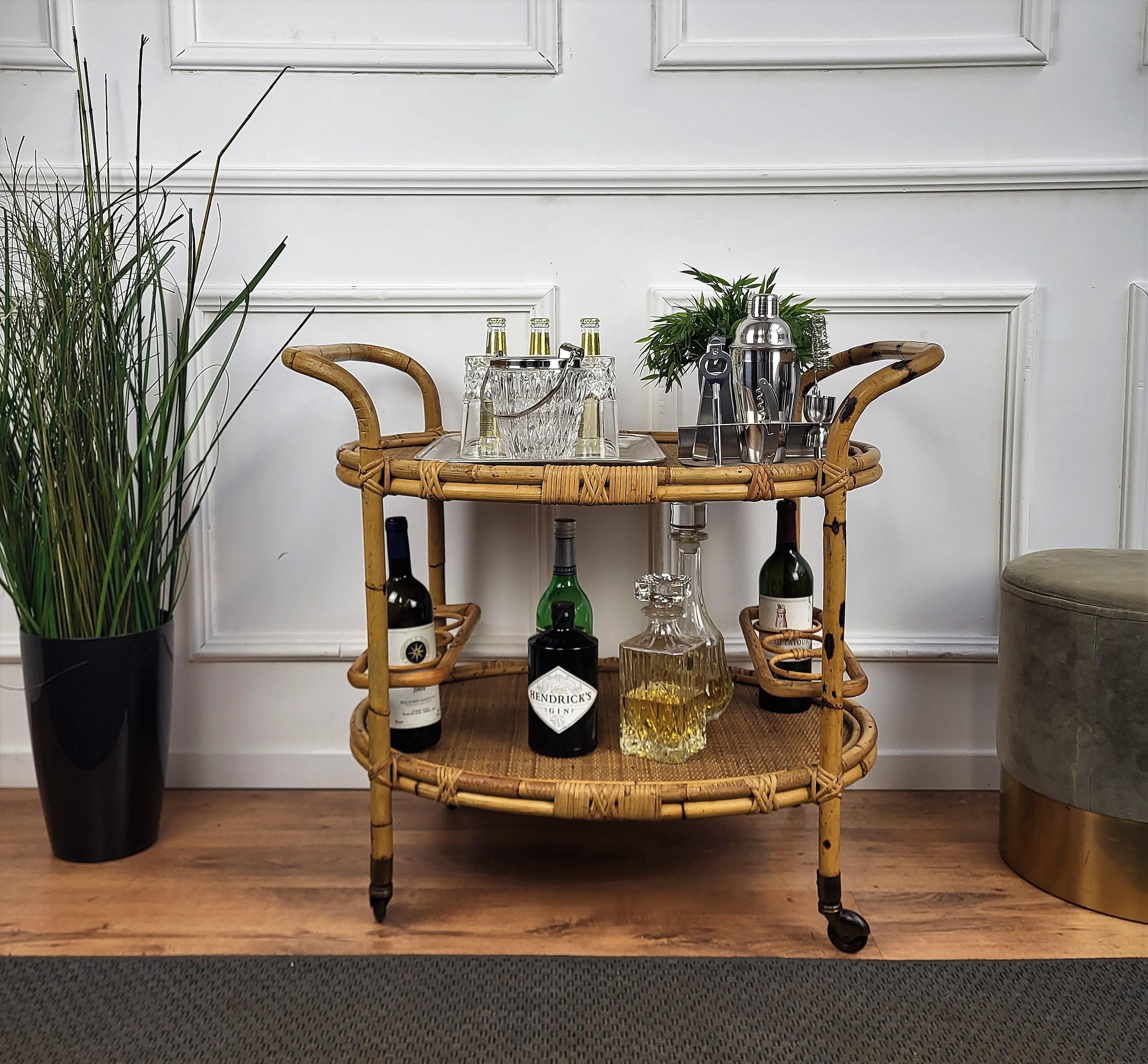 Beautiful 1970s Italian Mid-Century Modern serving bar cart trolley probably by the Italian Vittorio Bonacina featuring two levels, with the bottom one with three bottle holders on each side. Made of rattan and bamboo. This charming piece is in the