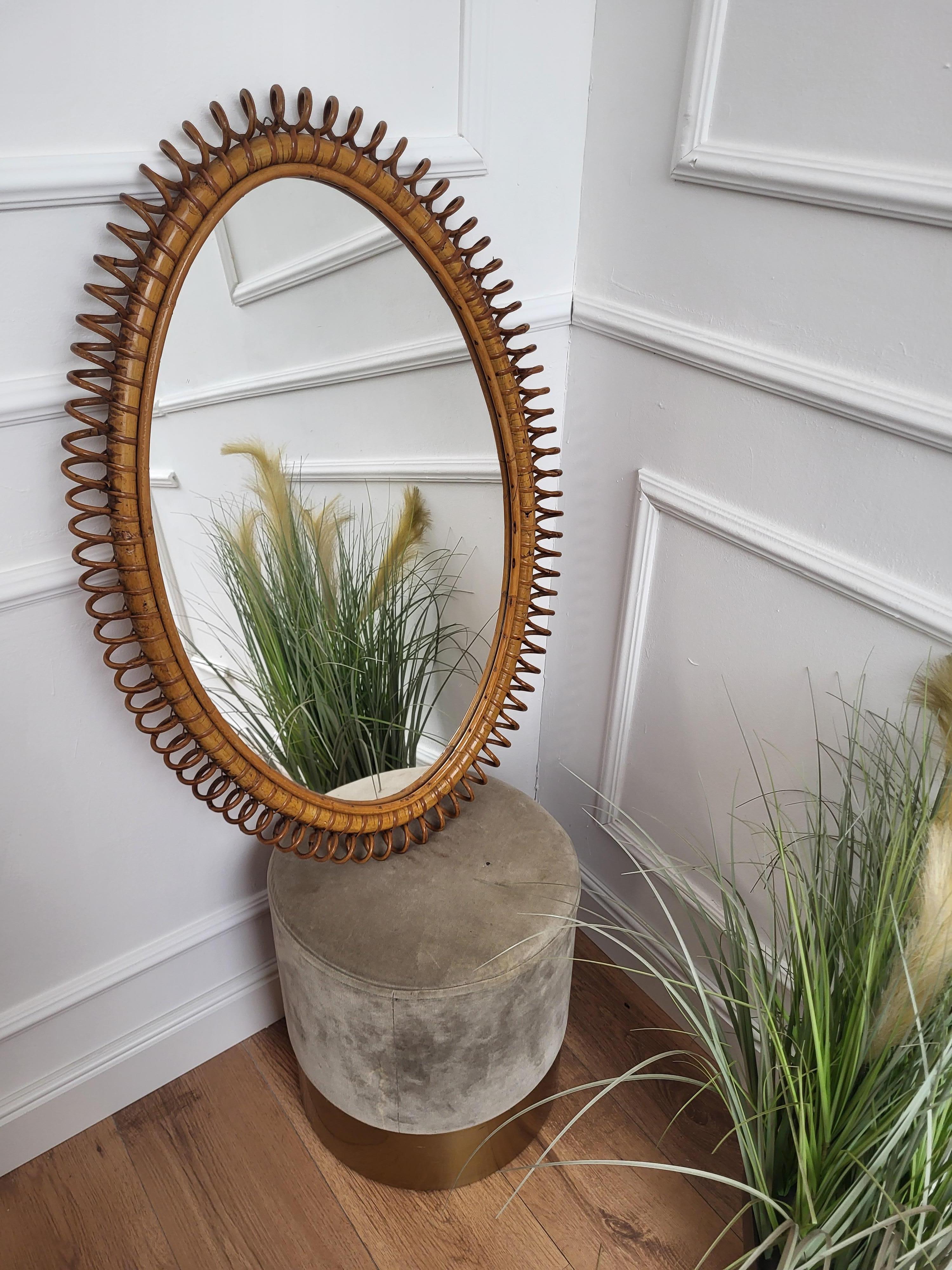Beautiful 1970s Italian Mid-Century Modern oval shaped wall mirror made of rattan and bamboo. This charming piece is in the typical style of Franco Albini, Adrien Audoux and Vittorio Bonacina where the organic beauty of the woven materials is