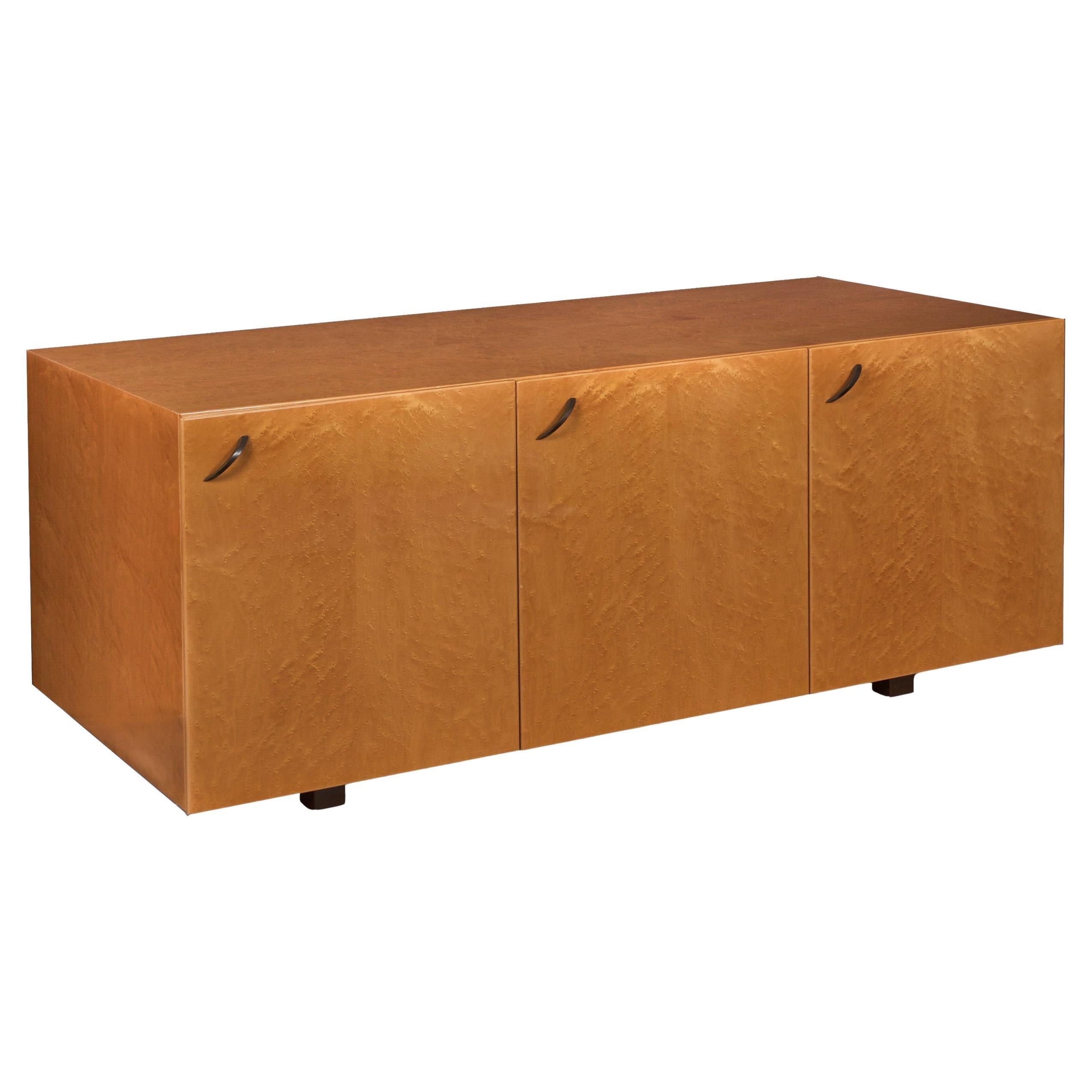 A delightful three-door credenza designed by Giovanni Offredi for Saporiti entirely in birdseye-maple veneered surfaces, it is a brilliant piece that absolutely glows under the shimmering acrylic varnish surface throughout. The doors are set with