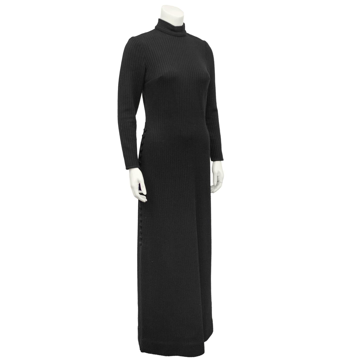Superbe robe noire en tricot côtelé des années 1970, de la créatrice italienne Lucia Knitting Mills. Col bénitier, manches longues et boutons recouverts le long de la jambe gauche. Fléchettes au niveau du buste. fente de 19