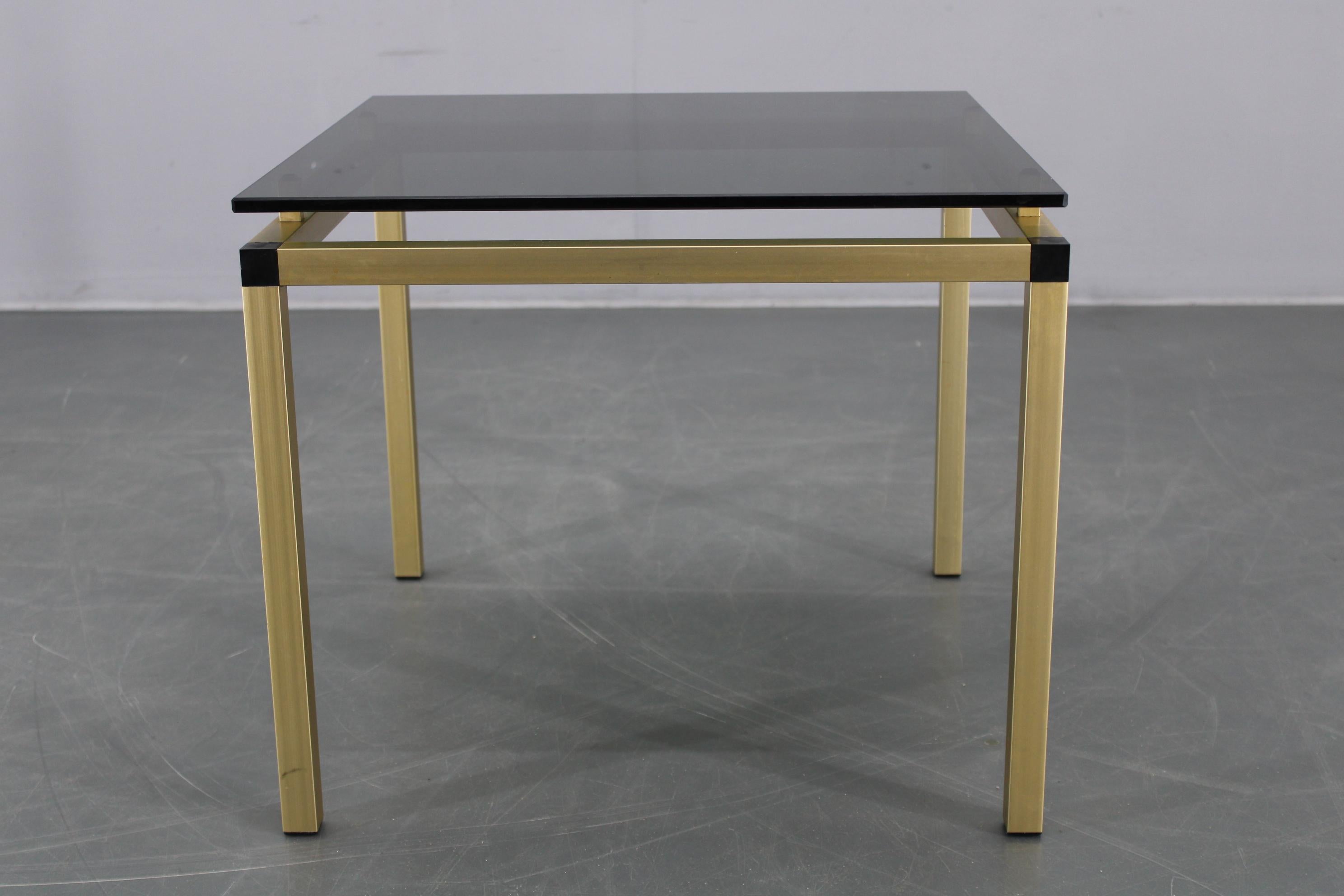 Table basse ou d'appoint italienne fabriquée dans les années 1970, dotée d'un cadre squelettique robuste en aluminium fini en laiton mat et d'un plateau en verre fumé foncé. 
Avec ses lignes épurées et ses matériaux remarquables, cette table capture