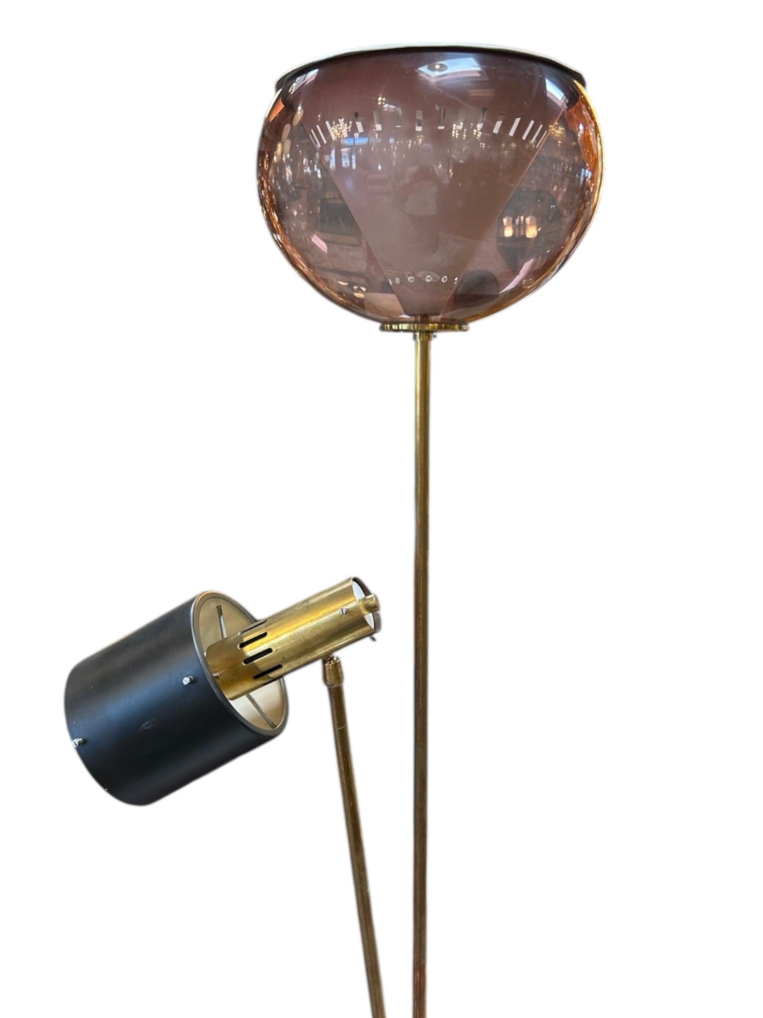 Questa lampada da terra italiana degli anni '70 è un esempio lampante di design modernista abbinato a un'attenta funzionalità. L'elegante struttura a due montanti in ottone si erge da una scultorea base in marmo bianco, offrendo una raffinatezza