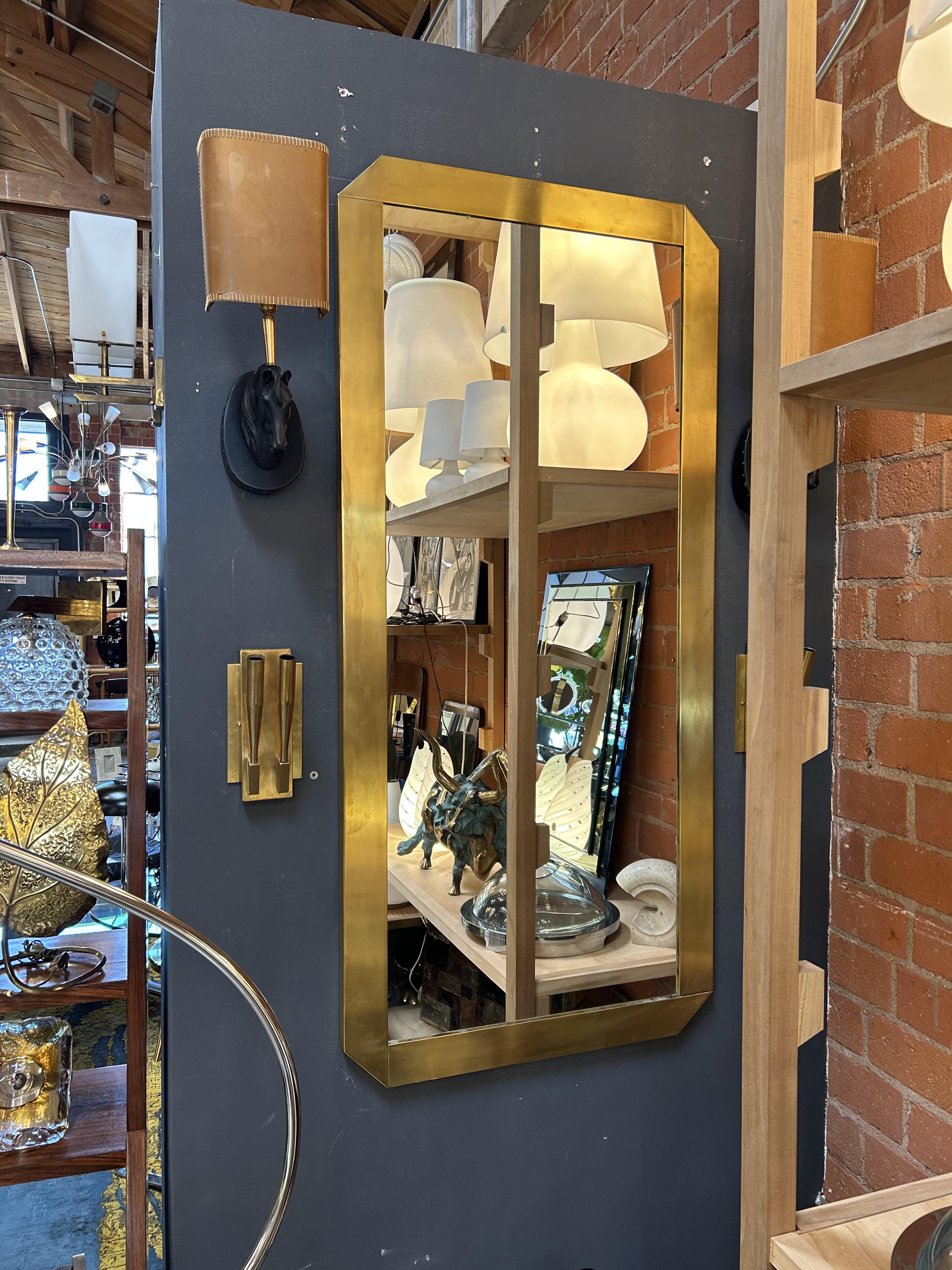 Questo straordinario specchio italiano, probabilmente realizzato negli anni '70, incarna l'audace eleganza dell'epoca con la sua forma geometrica e la lussuosa cornice in ottone. Il bordo spesso e angolare aggiunge profondità e dimensione, creando