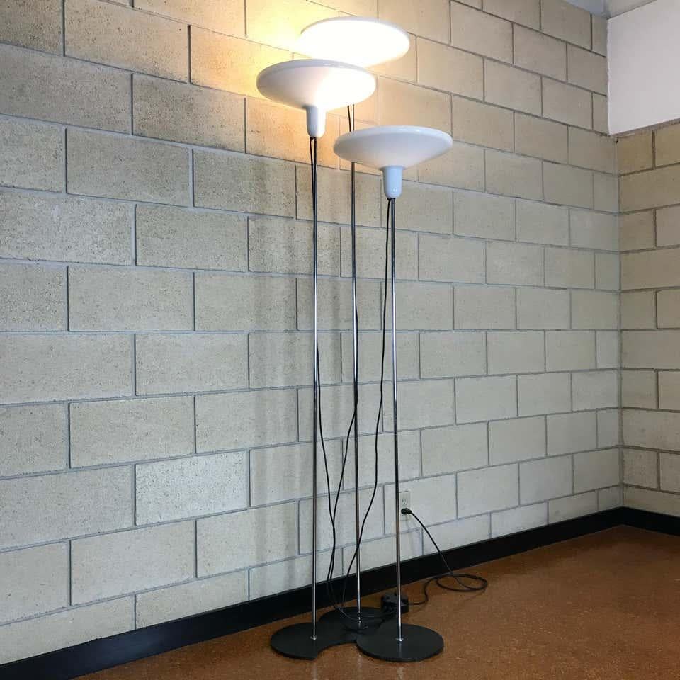 Beautiful set of three Italian modern floor lamps made of metal and acrylic by Harvey Guzzini for Harveiluce; Made in Italy. Each lamp is on an iron half-moon style base that allows it to nest with the other two lamps to create the design you