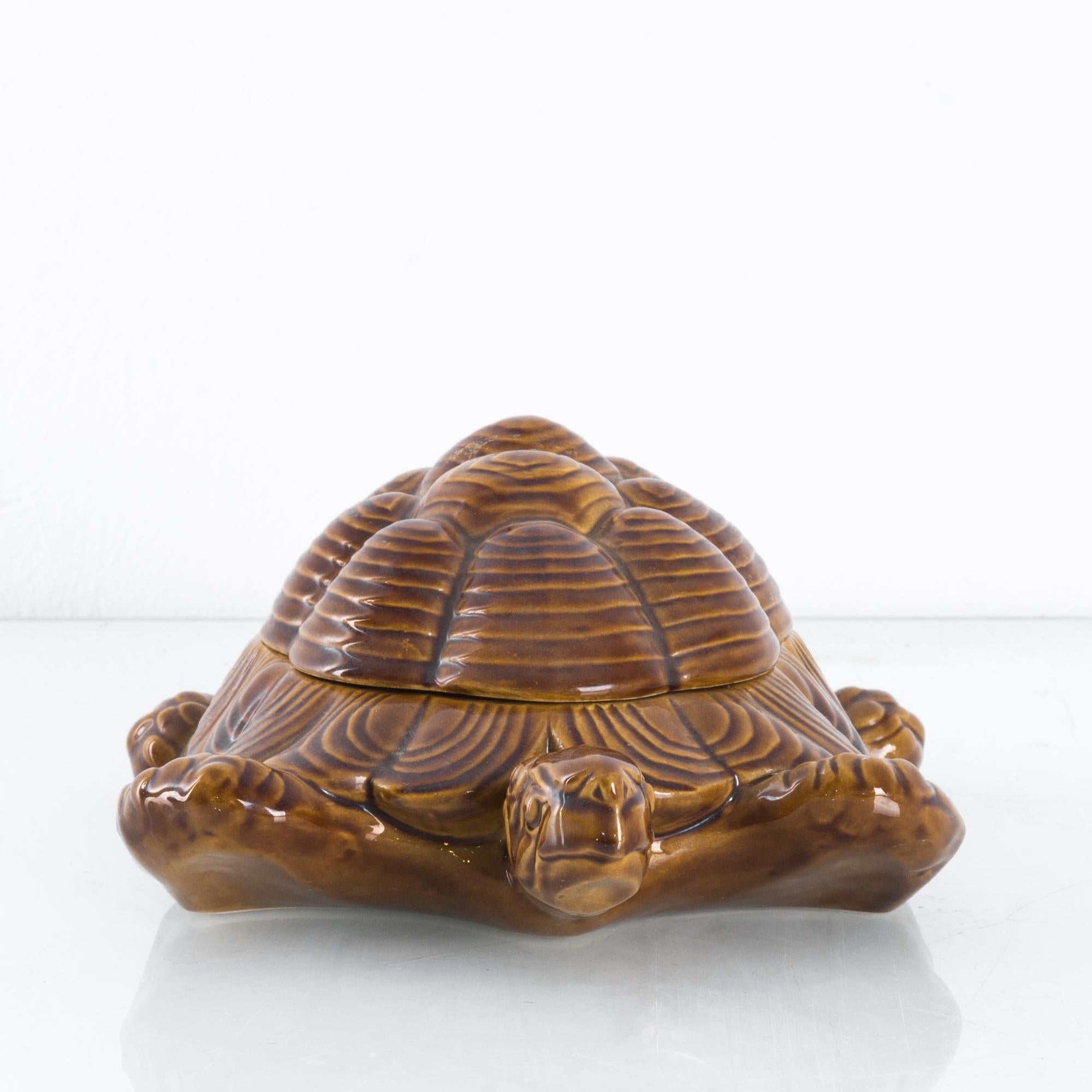 A ceramic turtle storage box from Italy, circa 1970. The shell of the turtle lifts to reveal a generous interior compartment. Head raised in an engaging gesture, the intricate ripples and patterns of the turtle’s shell and flippers are accentuated