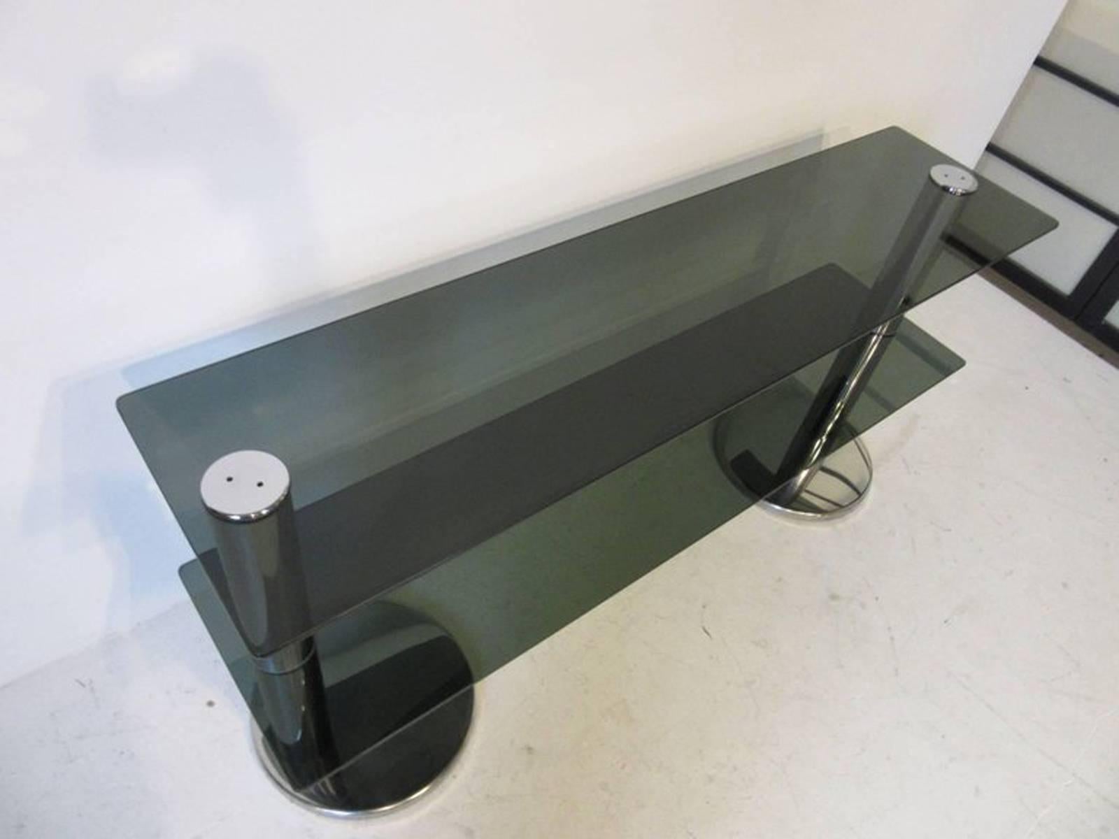 A chrome and glass console table or TV and entertainment stand with two shelves and rounded chrome bases. Very well-made and stabile a great design from the period and ready for a number of application.