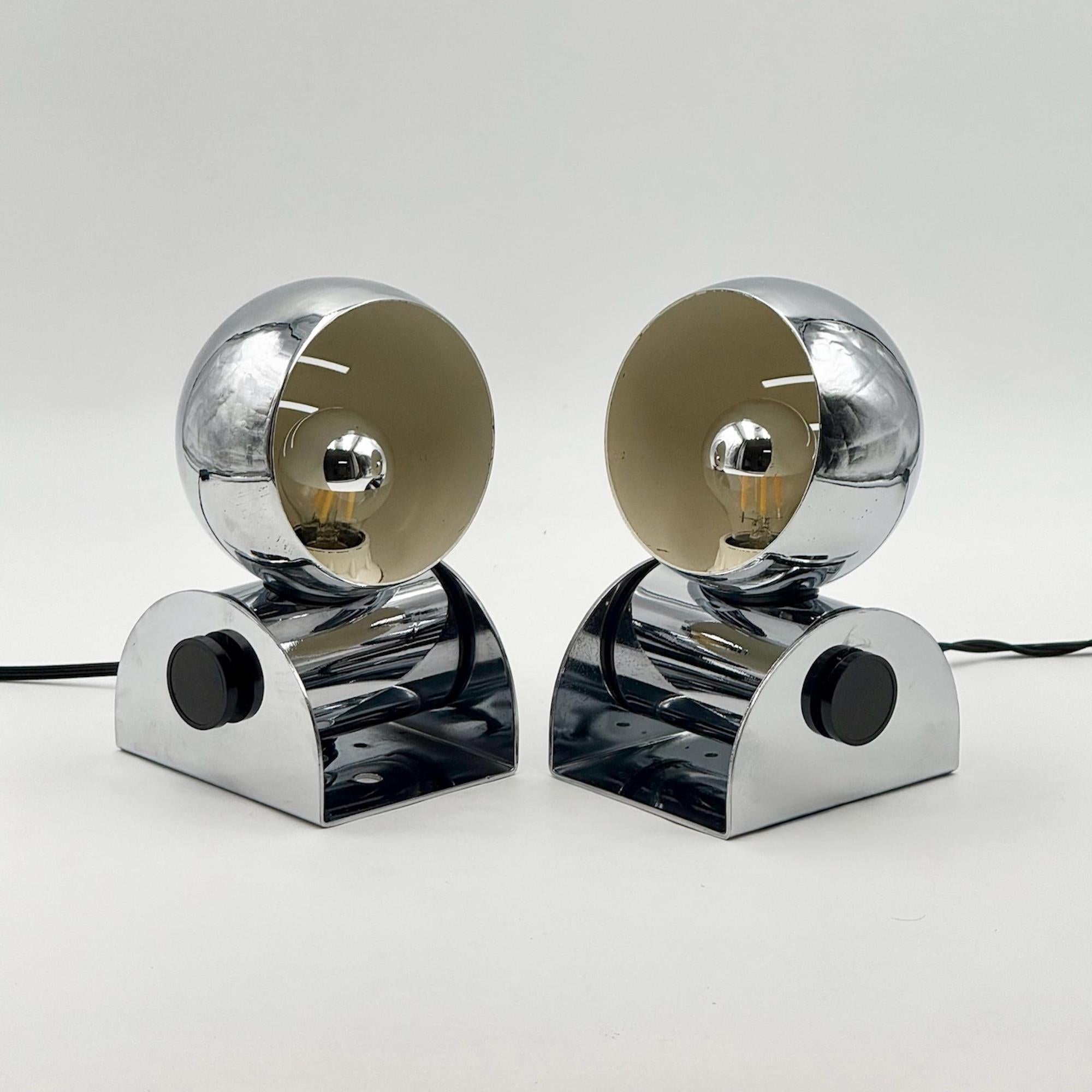 In questa occasione viene offerta una coppia di lampade da tavolo cromate italiane a forma di bulbo oculare di Tronconi, risalenti al periodo dell'A Space Age degli anni '70. Ogni lampada combina una base ad arco in metallo cromato con una testa